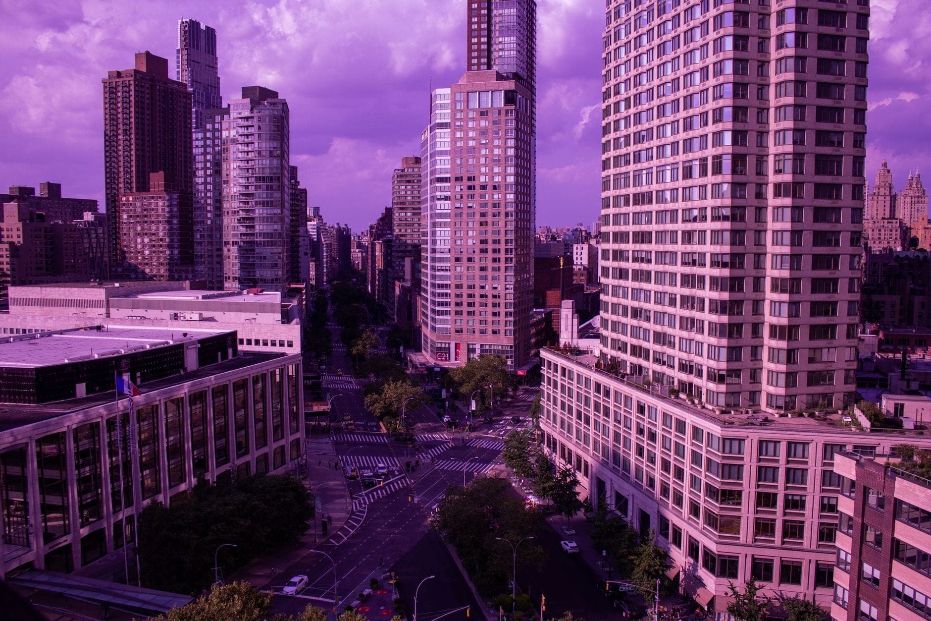 วิวกว้างของ Lincoln Center และอาคารสูงโดยรอบในนครนิวยอร์ก ถ่ายในช่วงพลบค่ำพร้อมโทนสีม่วงอมชมพูเหนือเส้นขอบฟ้าของเมือง