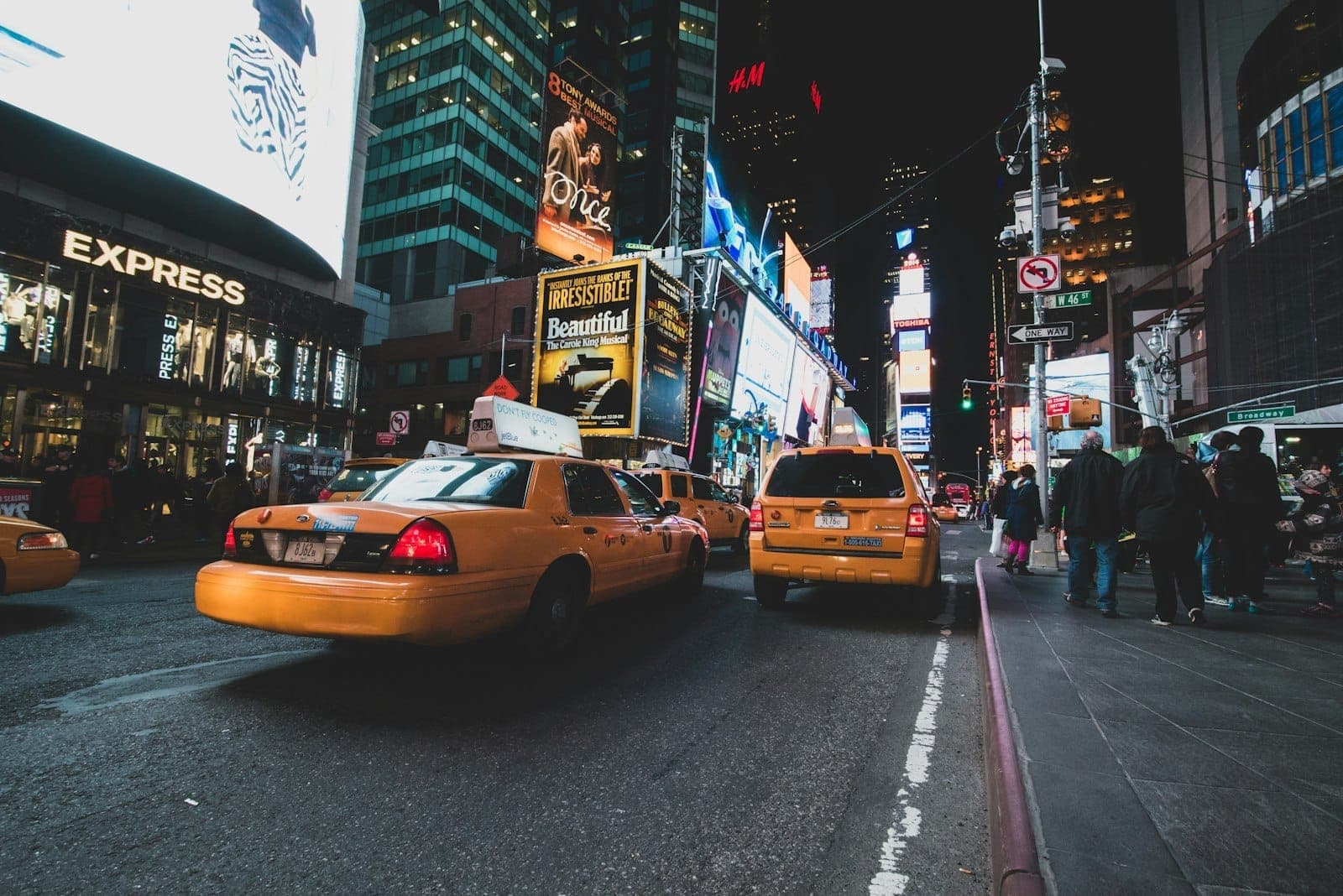 วิวยามค่ำคืนของ Times Square พร้อมแท็กซี่สีเหลือง แสงไฟสว่างไสว และป้ายโฆษณาใน Midtown Manhattan นครนิวยอร์ก