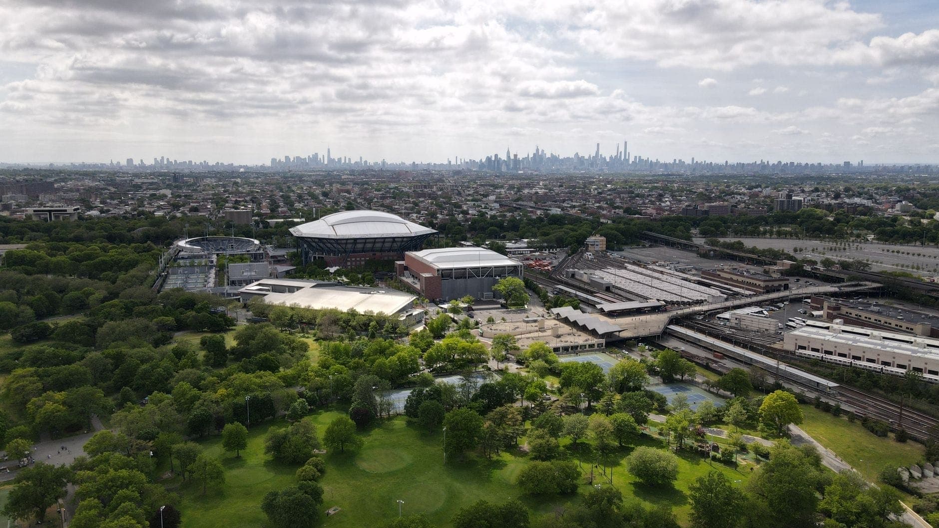มุมมองทางอากาศของ USTA Billie Jean King National Tennis Center พร้อม Arthur Ashe Stadium ล้อมรอบด้วย Flushing Meadows–Corona Park ในควีนส์ นครนิวยอร์ก