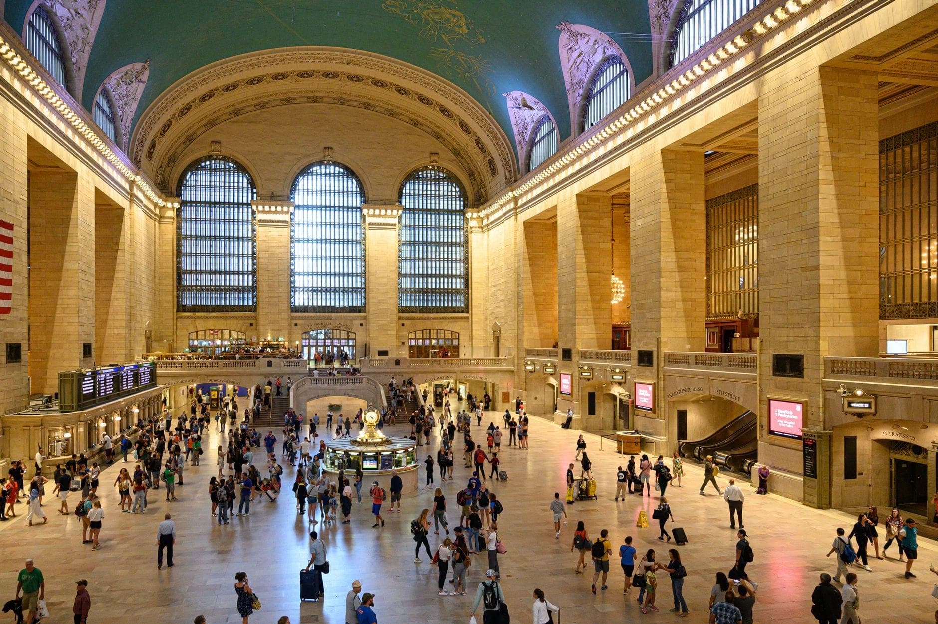 มุมมองไวด์แองเกิลของห้องโถงหลักของ Grand Central Terminal ที่คึกคักด้วยผู้คนใต้เพดานโค้งที่ประดับด้วยกลุ่มดาวและหน้าต่างโค้งขนาดใหญ่