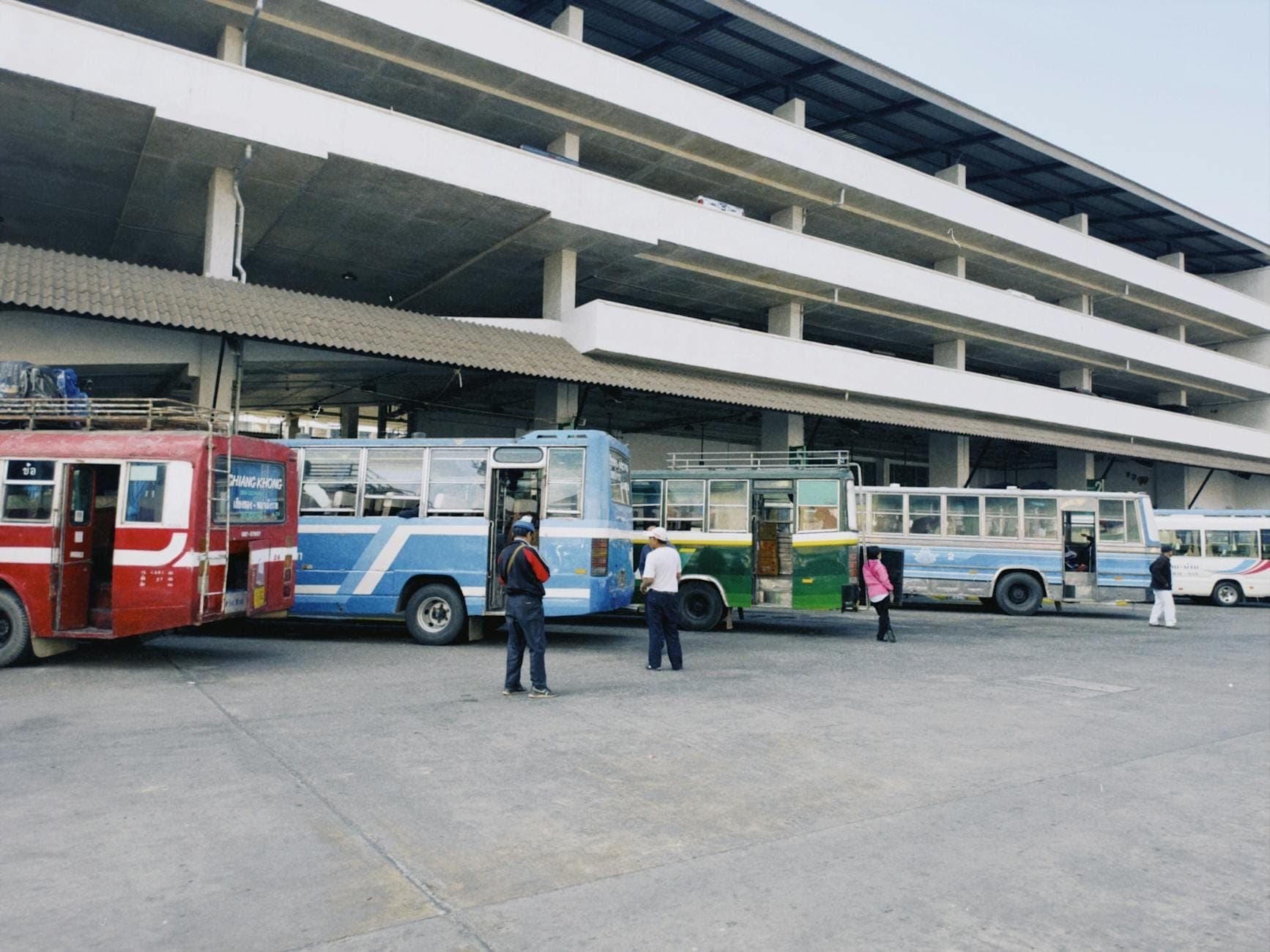 Filas de autobuses y personas esperando fuera de una grande y moderna terminal de autobuses, probablemente en Chiang Mai, Tailandia.