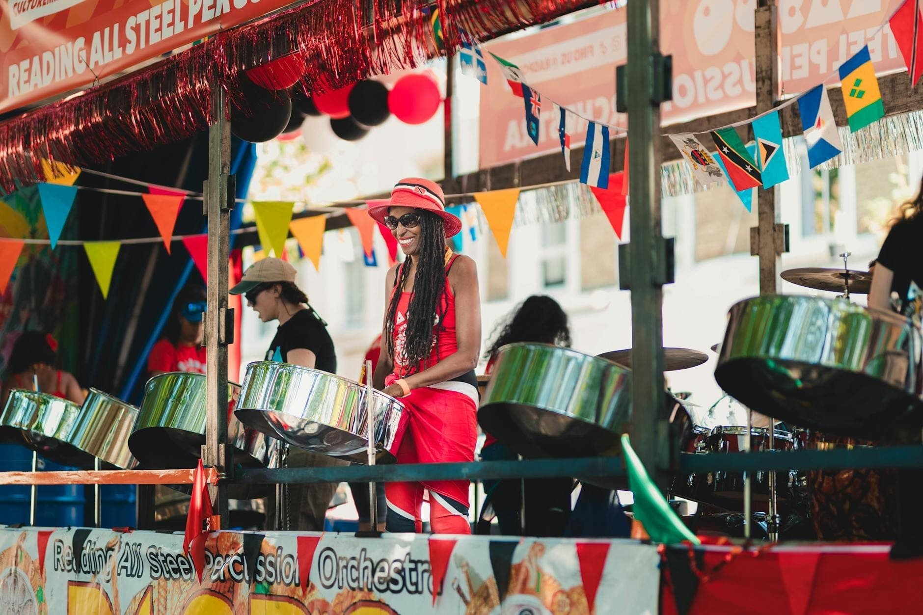 Una animada banda de steel drums actúa sobre una carroza decorada con banderas de colores en el Carnaval de Notting Hill, capturando el ambiente festivo y vibrante del evento.