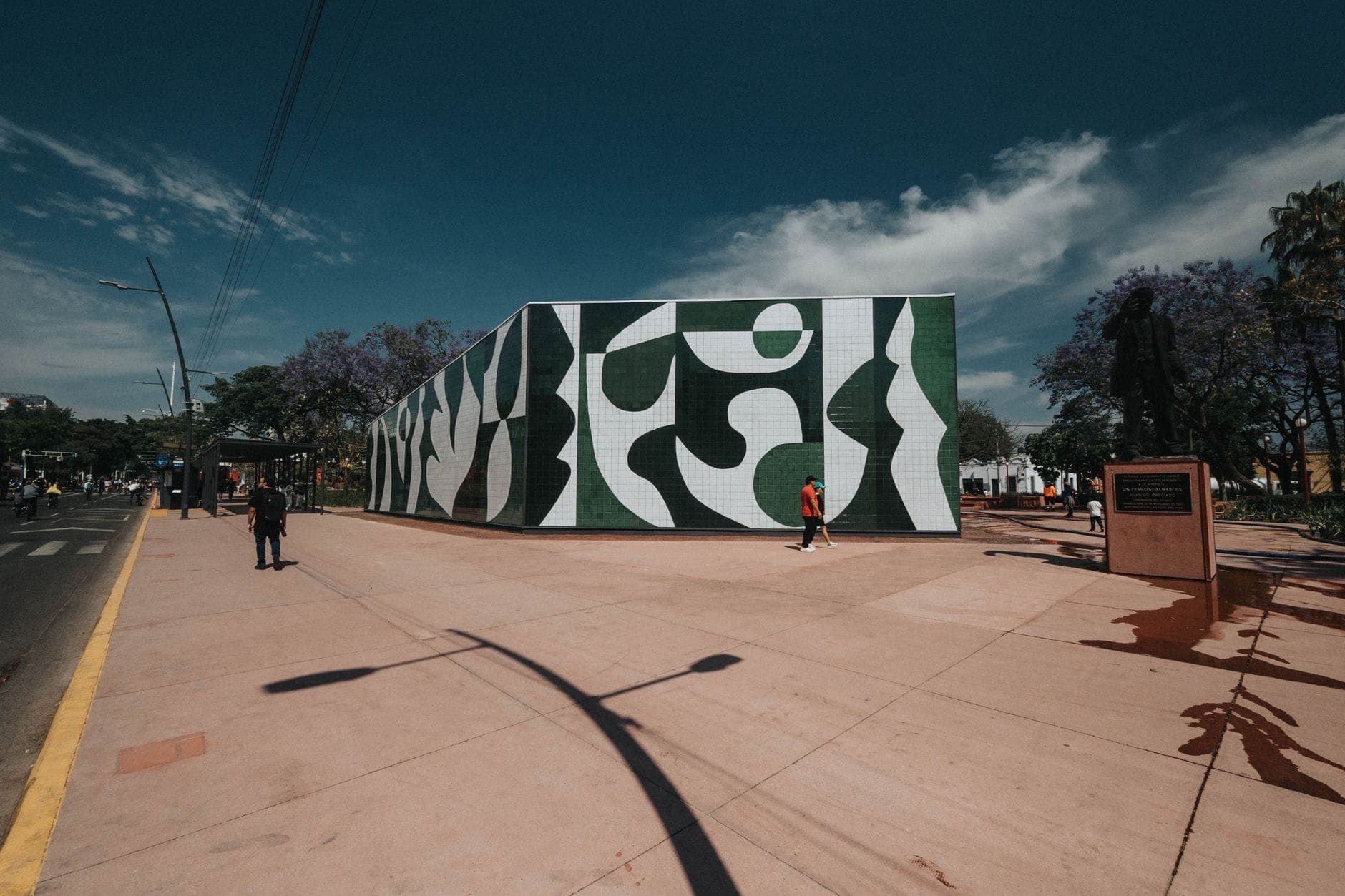 รูปปั้นด้านหน้าอาคารจิตรกรรมฝาผนังแบบแอบสแตรกต์สีเขียวและขาวที่ Parque Revolución เมือง Guadalajara ใต้ท้องฟ้าสีฟ้าแจ่มใส