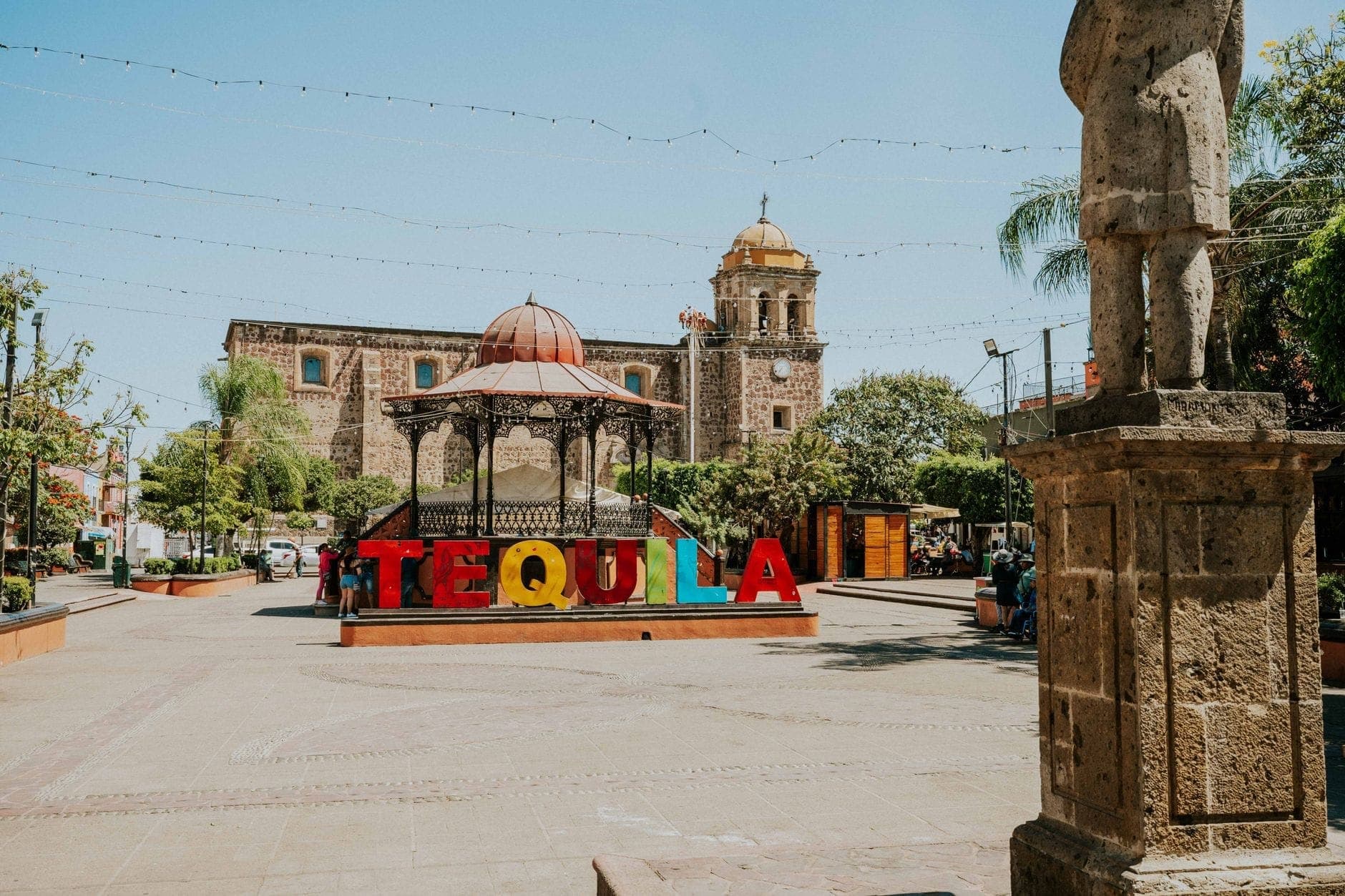 บรรยากาศจัตุรัสกลางเมือง เตกีลา สีสันสดใส มีป้าย 'TEQUILA' ศาลากลาง และโบสถ์เก่าแก่ฉากหลัง ท้องฟ้าปลอดโปร่ง