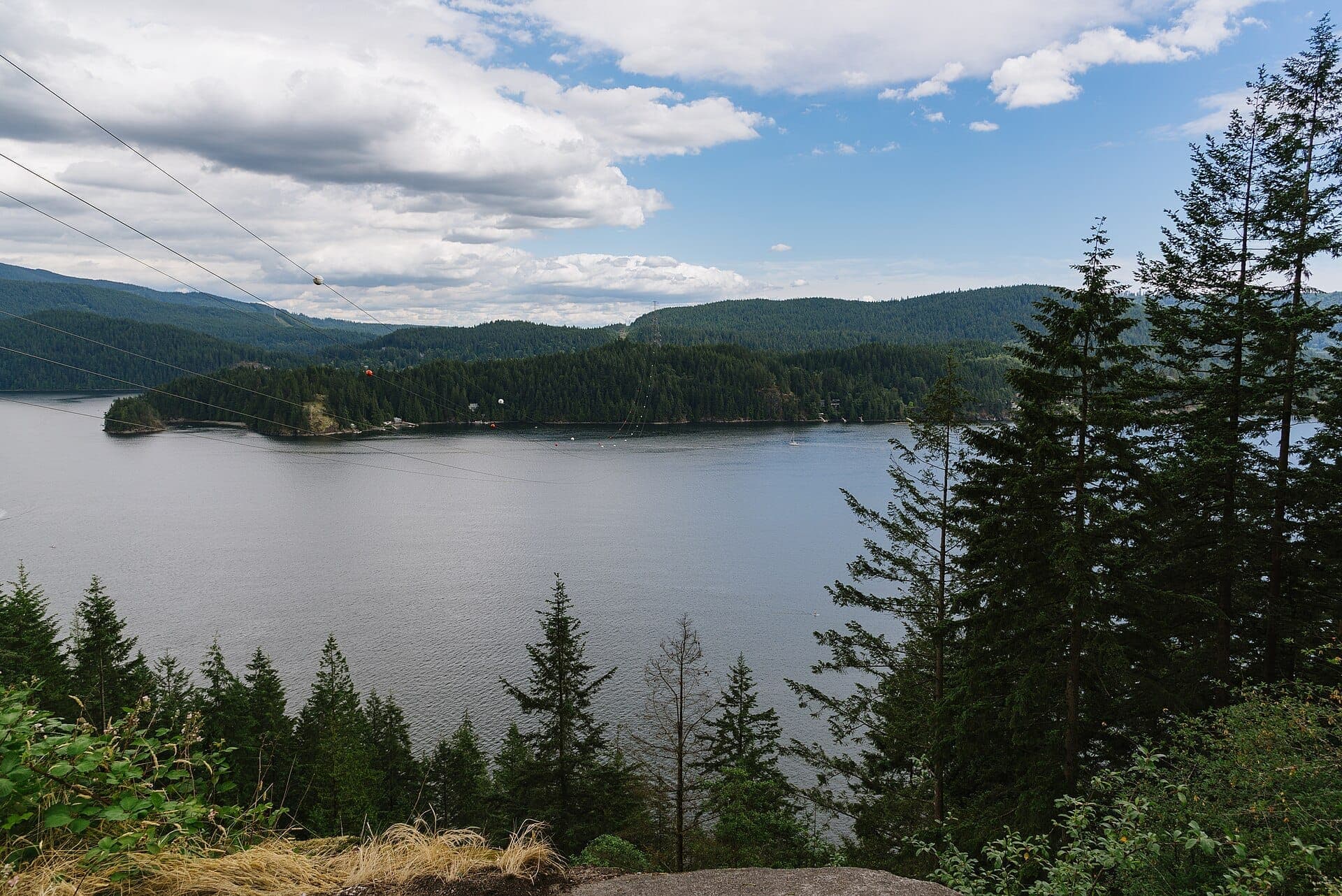 วิวจาก Quarry Rock มองเห็น Indian Arm พร้อมน้ำที่สงบ ต้นไม้สนสูง เนินเขาที่ปกคลุมด้วยป่า และท้องฟ้าที่มีเมฆบางส่วน