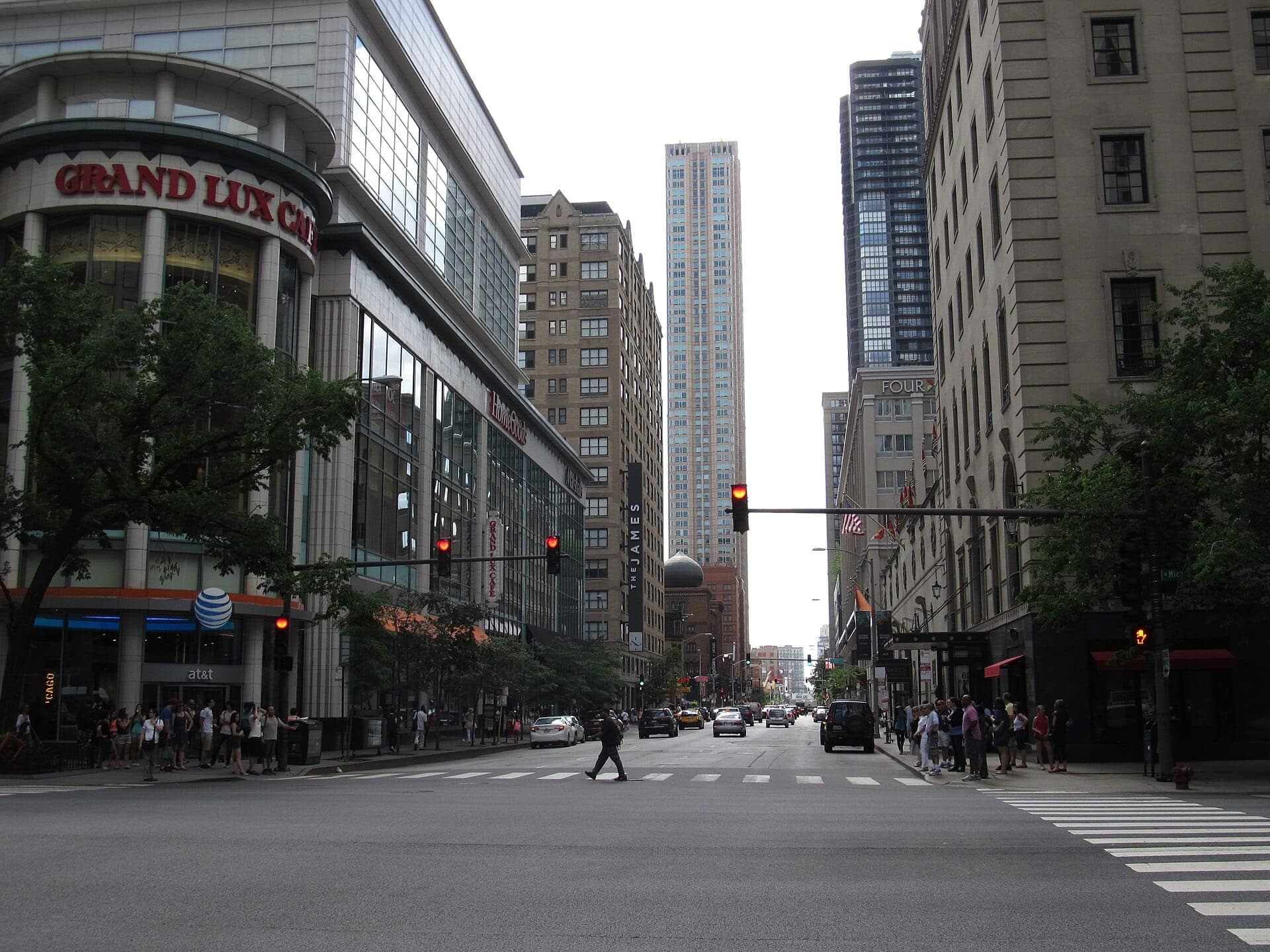 Intersection in Chicago’s River North Gallery District with tall buildings, storefronts like Grand Lux Cafe, streetlights, and people waiting to cross.