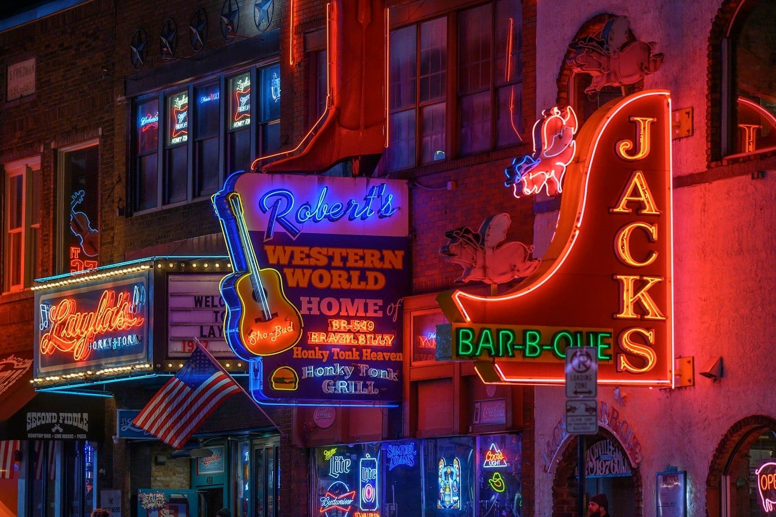 Bright neon signs of Robert’s Western World and nearby honky-tonks light up Nashville’s Broadway at night, capturing the authentic nightlife and vibrant music scene.