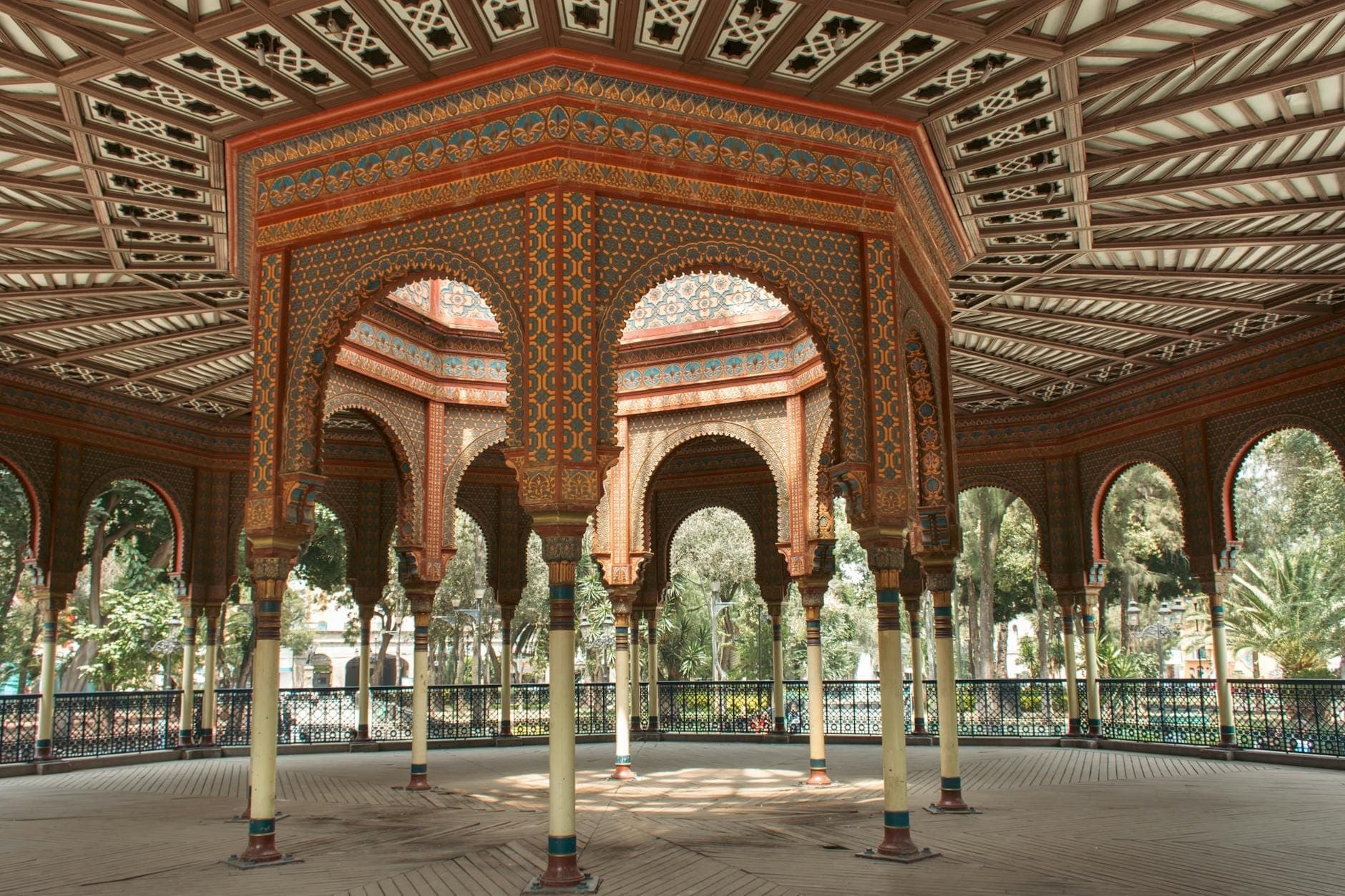 มุมมองภายในของ Kiosco Morisco ในเม็กซิโกซิตี้ โชว์ลายเสาโค้งมัวร์ ดีไซน์แปดเหลี่ยม ลวดลายซับซ้อน แสงธรรมชาติจ้า ในสวนร่มรื่น
