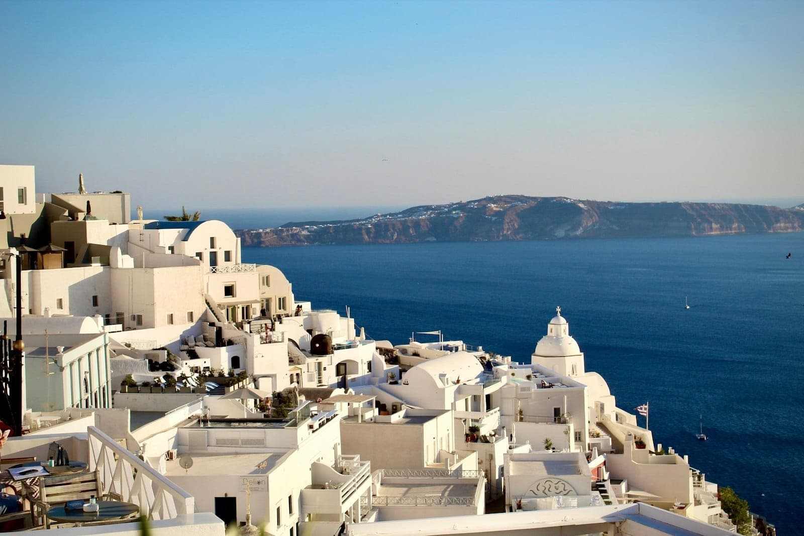 Weitwinkelpanorama über Santorins ikonische weiße Häuser mit blauen Kuppeln, mit Blick auf die Caldera und das tiefblaue Ägäische Meer an einem klaren Tag.