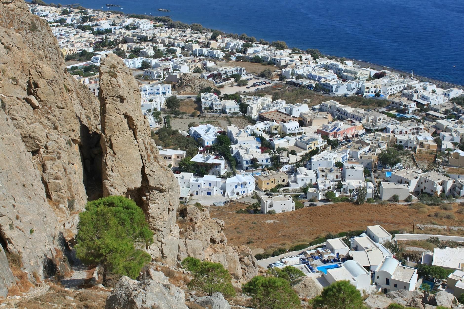 Vista amplia de la costa este de Santorini con numerosos edificios blancos y mar azul cristalino, una zona práctica para familias.