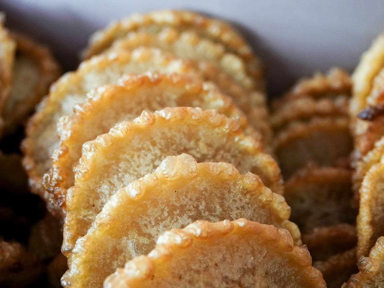 Vista de cerca de pasteles fritos dorados y redondos apilados ordenadamente, brillantes con miel, que recuerdan a las tradicionales seadas sardas.