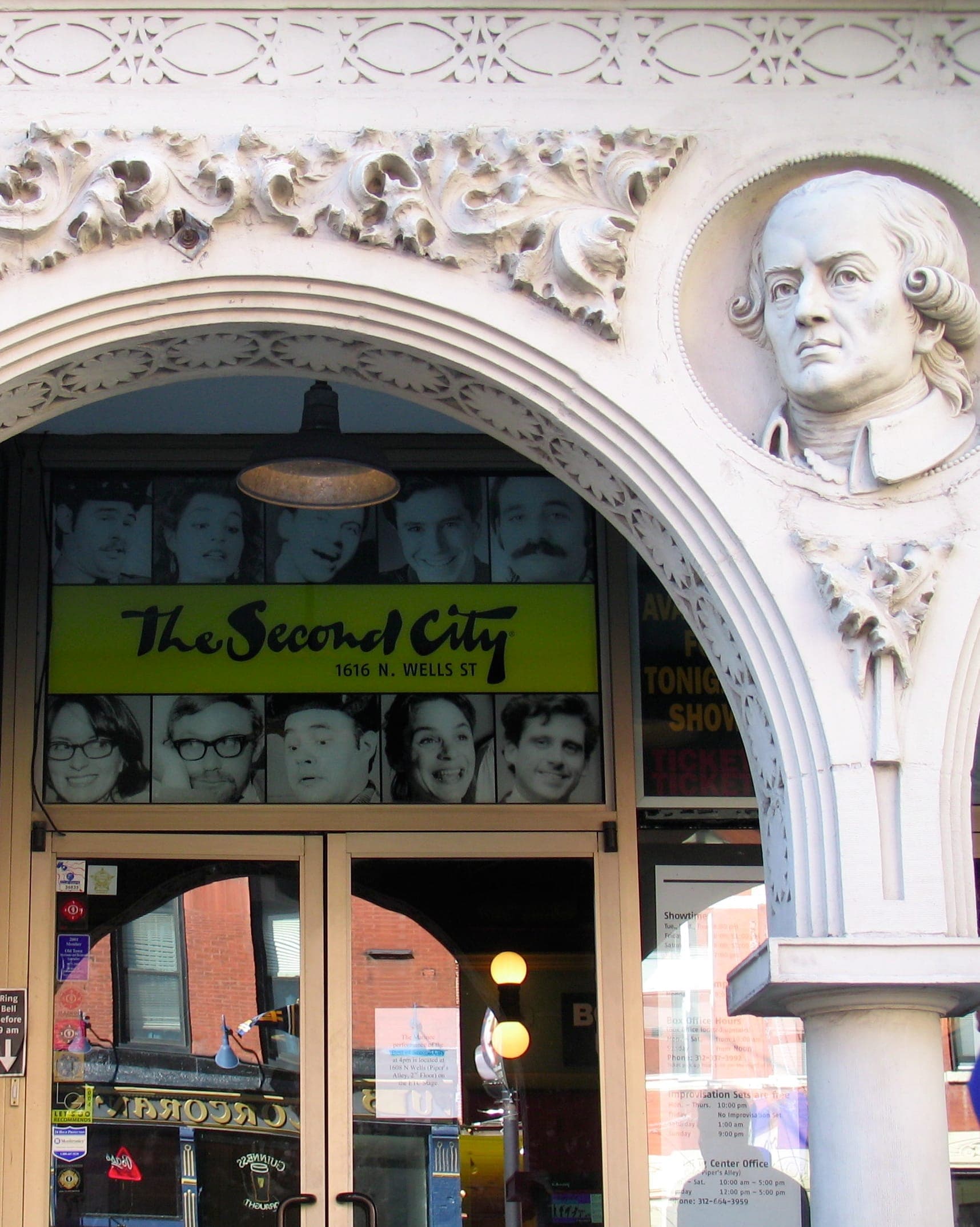 ทางเข้า The Second City ในย่าน Old Town ของชิคาโก โดดเด่นด้วยซุ้มประตูสีขาวประดับประดา รูปปั้นหินครึ่งตัว และภาพเหมือนของนักแสดงตลกชื่อดังเหนือประตูกระจก