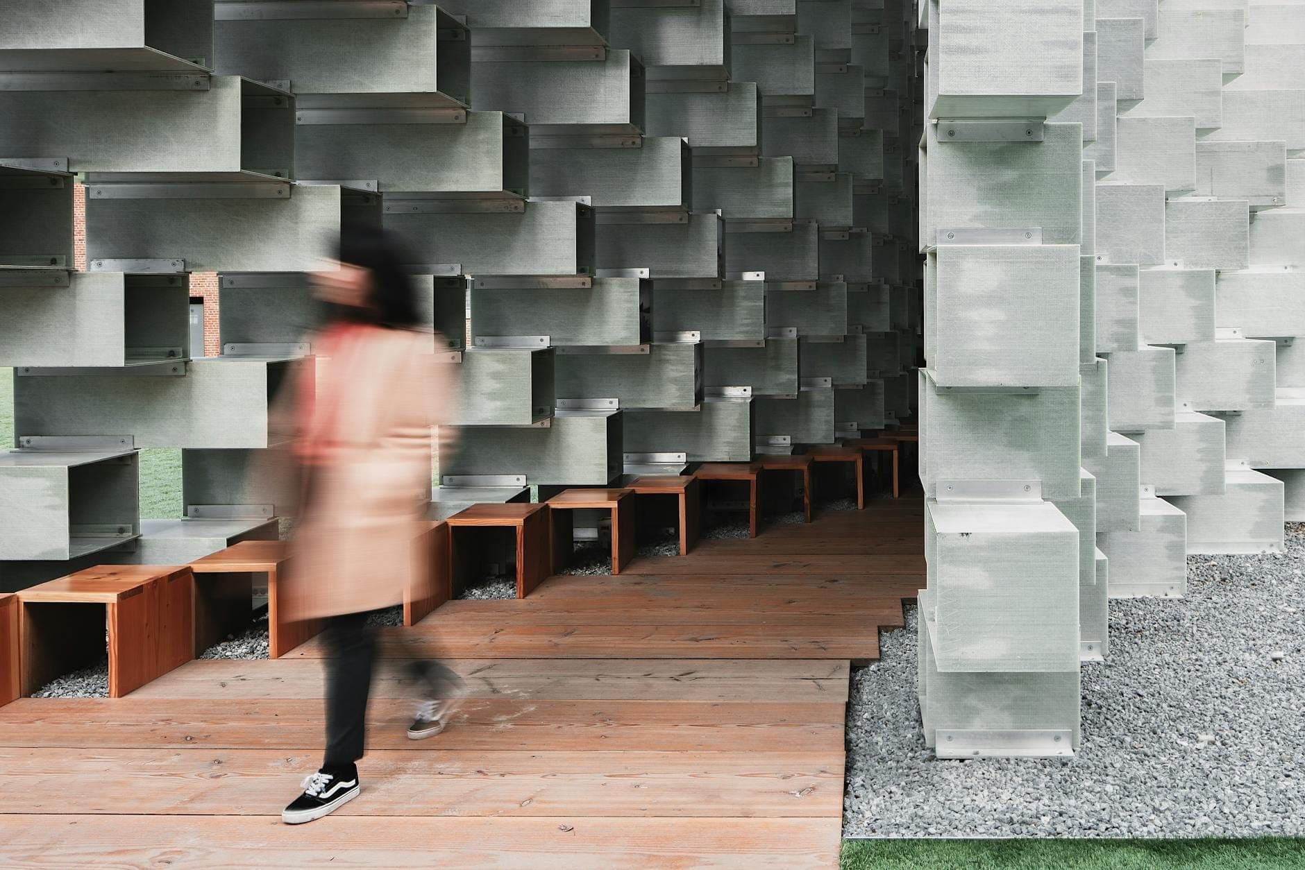 Eine Person geht durch den markanten geometrischen Pavillon der Serpentine Galleries – moderne Architekturdetails und natürliches Licht erfüllen den Raum.