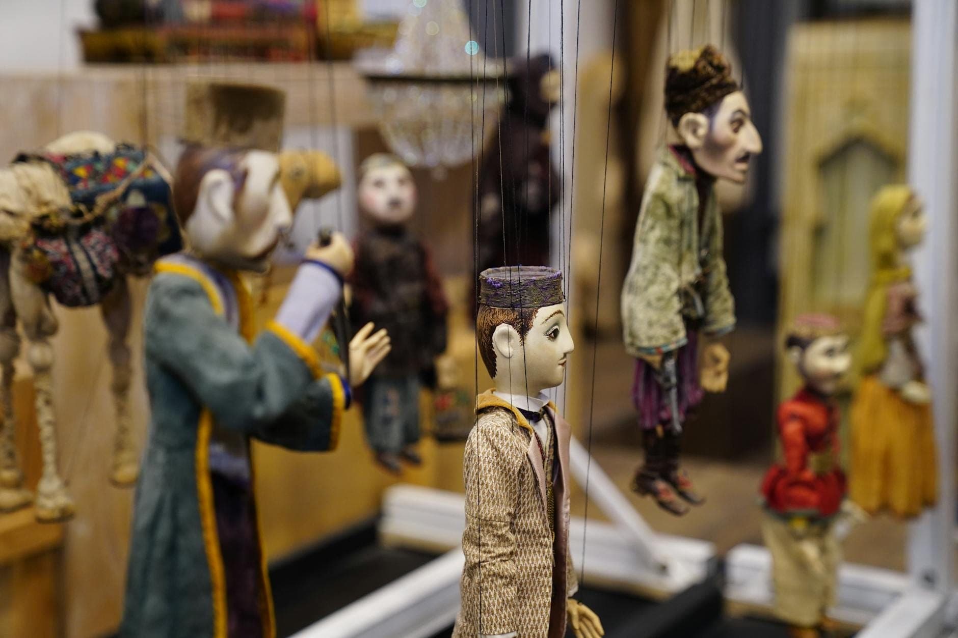 Tampak dekat boneka marionette Sisilia tradisional yang tergantung di sebuah bengkel, memperlihatkan kostum rumit dan ekspresi wajah yang hidup, mencerminkan keahlian seni Opera dei Pupi.