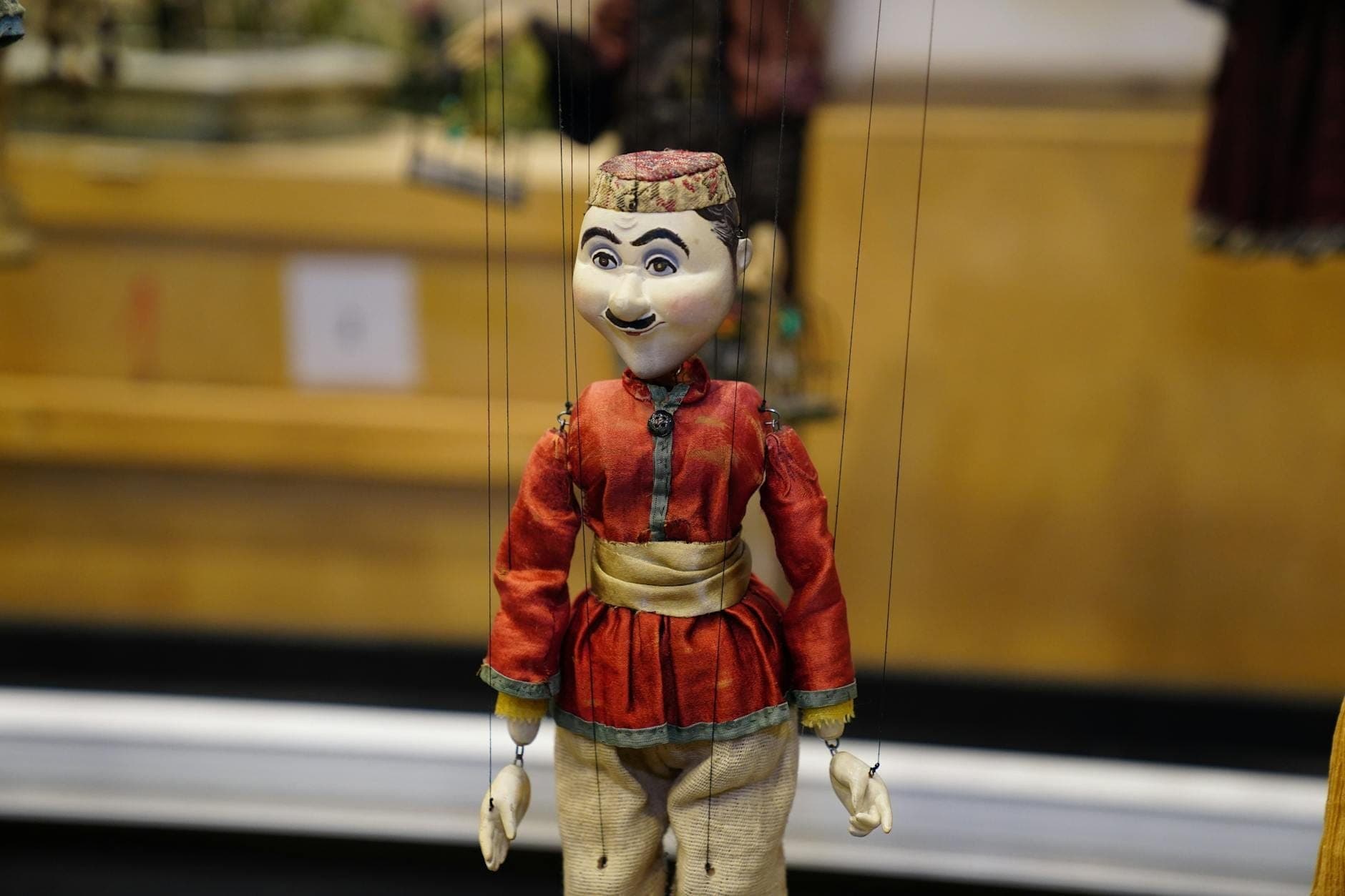Boneka marionette tradisional dengan kostum mewah, digantung dengan tali, berlatar belakang panggung teatrikal, khas teater boneka Mediterania atau Sisilia.