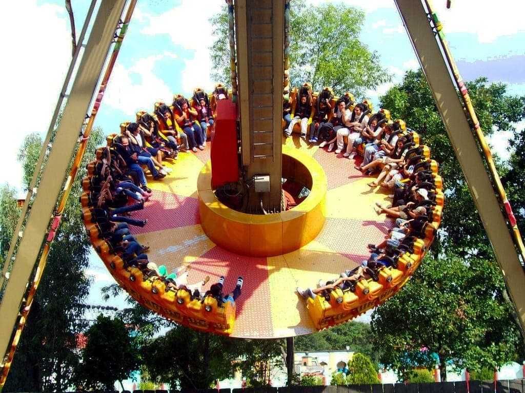 เครื่องเล่นสวนสนุกทรงกลมขนาดใหญ่ที่เต็มไปด้วยผู้คนใน Six Flags México ล้อมรอบด้วยต้นไม้สีเขียวและท้องฟ้าที่สดใสแจ่มใส