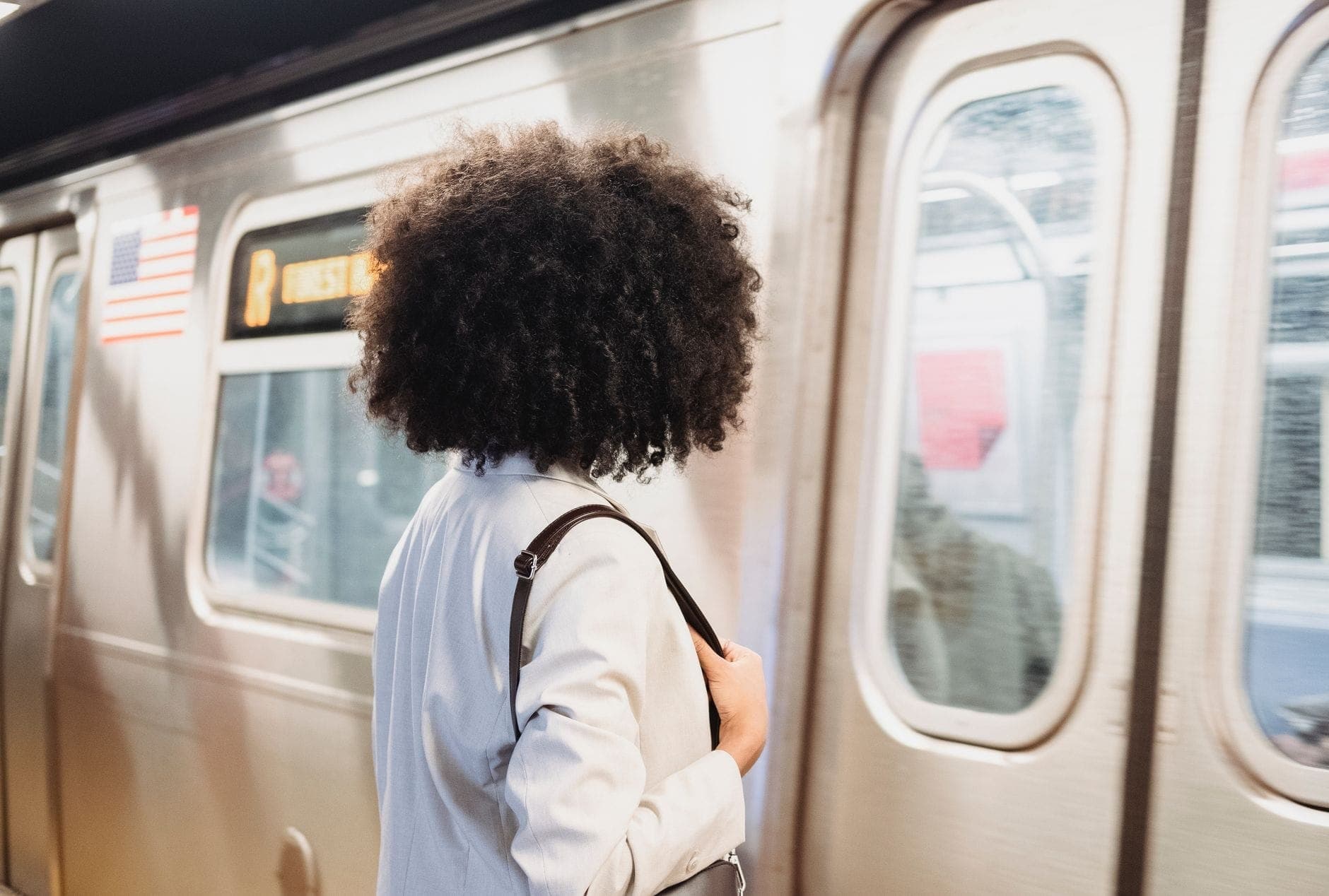 ผู้หญิงรอบนชานชาลารถไฟใต้ดินขณะที่รถไฟ NYC Subway สาย R แล่นเข้ามาในสถานี