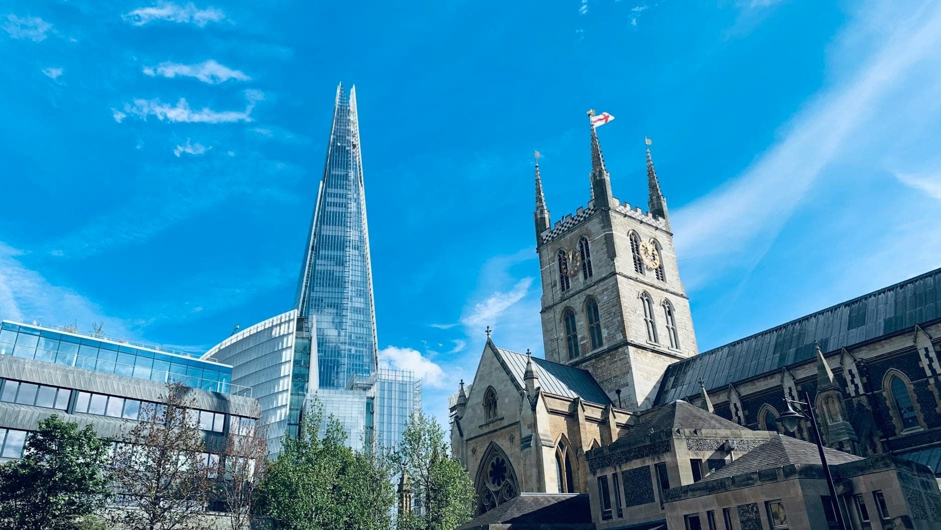 Widok na katedrę Southwark z gotycką wieżą i wieżowcem The Shard w tle, pod błękitnym niebem w Londynie.