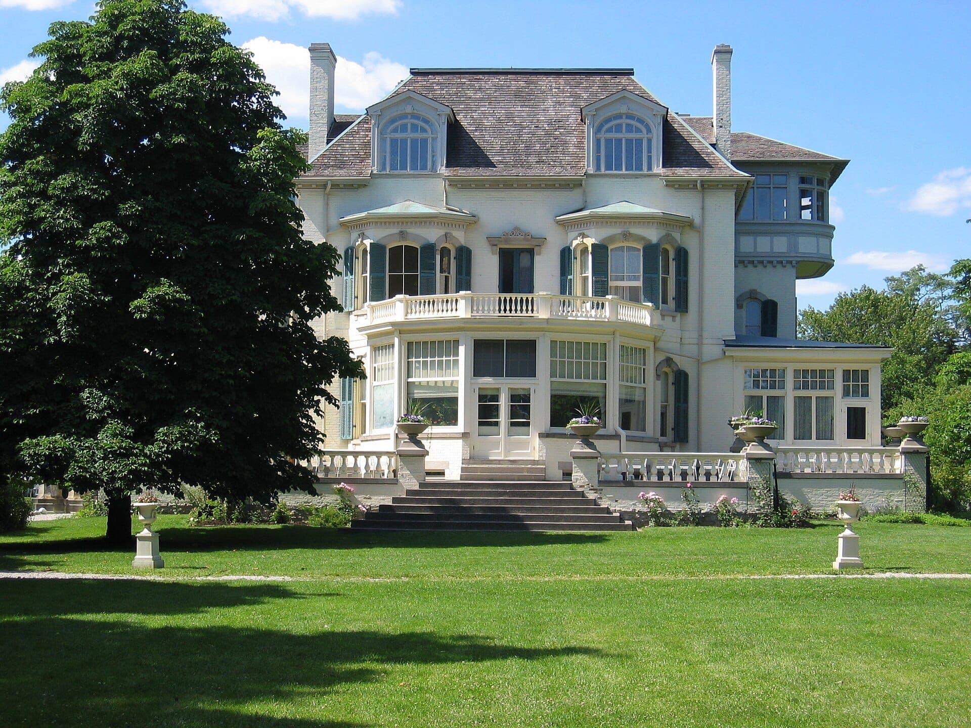 Vista frontale dello Spadina Museum, una grande villa storica con finestre ornate e giardini, sotto un cielo azzurro limpido a Toronto.