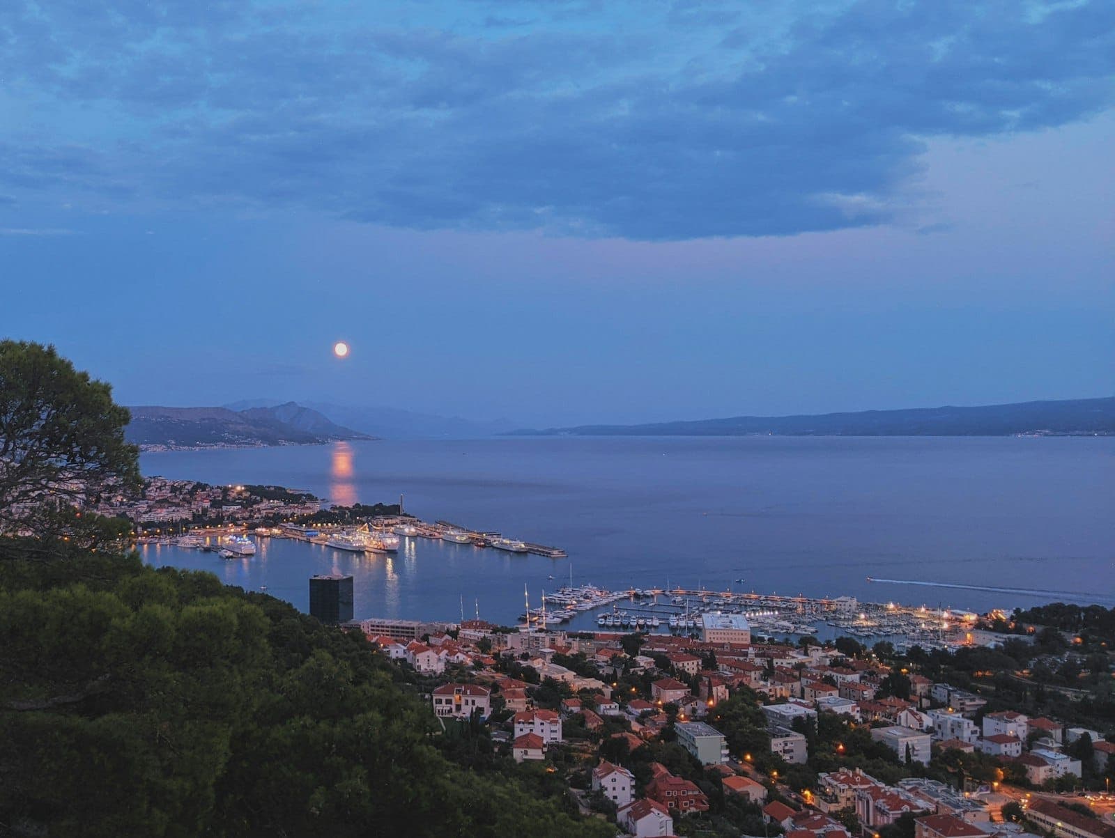 Vue aérienne de Split, en Croatie, au crépuscule : lumières de la ville, port et reflet de la lune sur l'Adriatique, pour une atmosphère résolument festive.