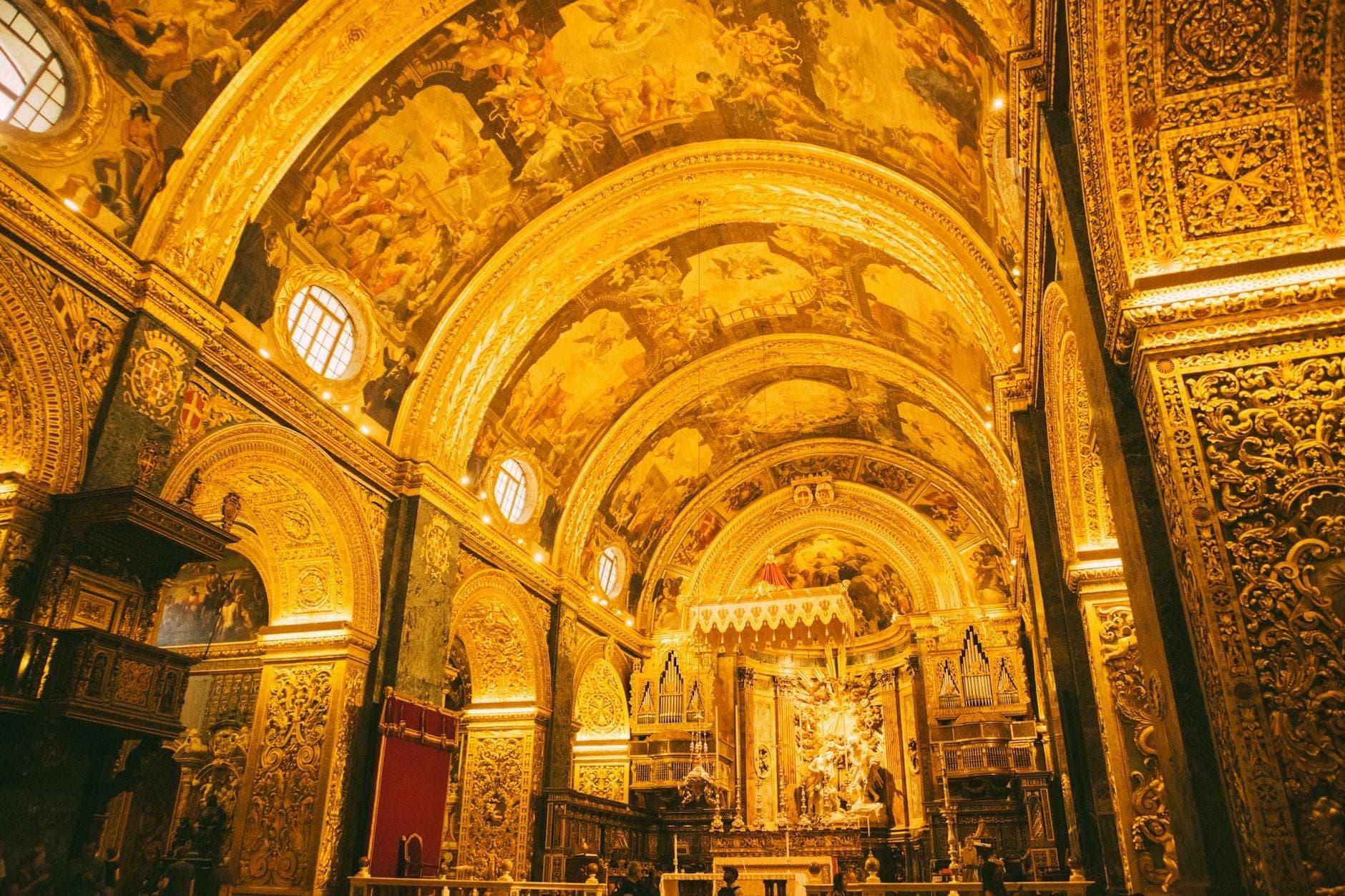 Üppig vergoldetes Barockinneres der St. John's Co-Kathedrale in Valletta mit prächtigen Bögen, reich verzierten Decken und dem in goldenes Licht getauchten Hauptaltar.