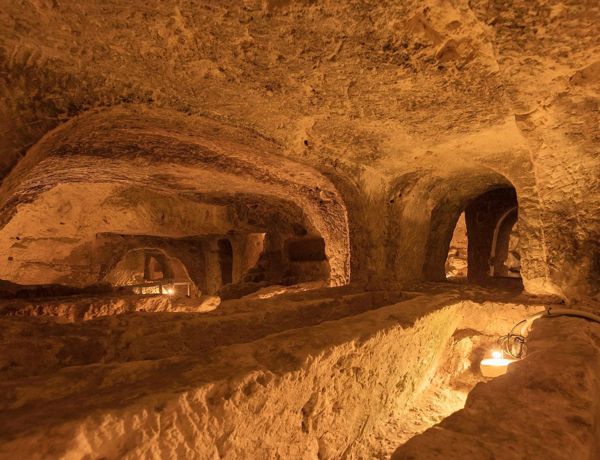 Blick auf die St. Paul's Catacombs in Rabat, Malta, mit handgehauenen Kalksteintunneln und Grabkammern, die in warmem Licht erstrahlen.