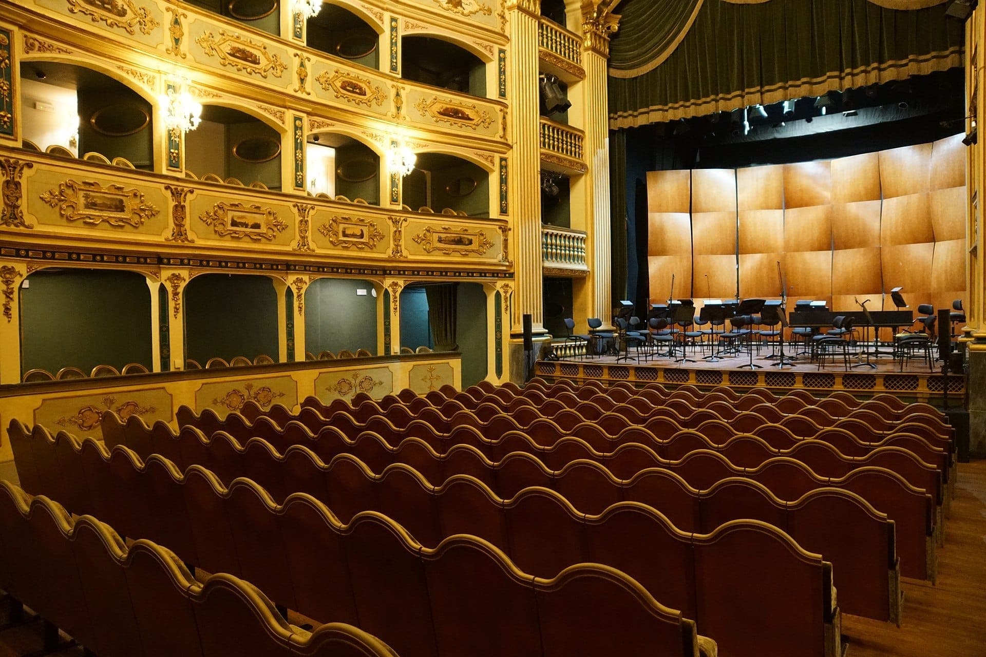 Reihen verzierter roter Samtsessel blicken auf die Holzbühne des Teatru Manoel, umgeben von barocken Balkonen und goldenen Details.