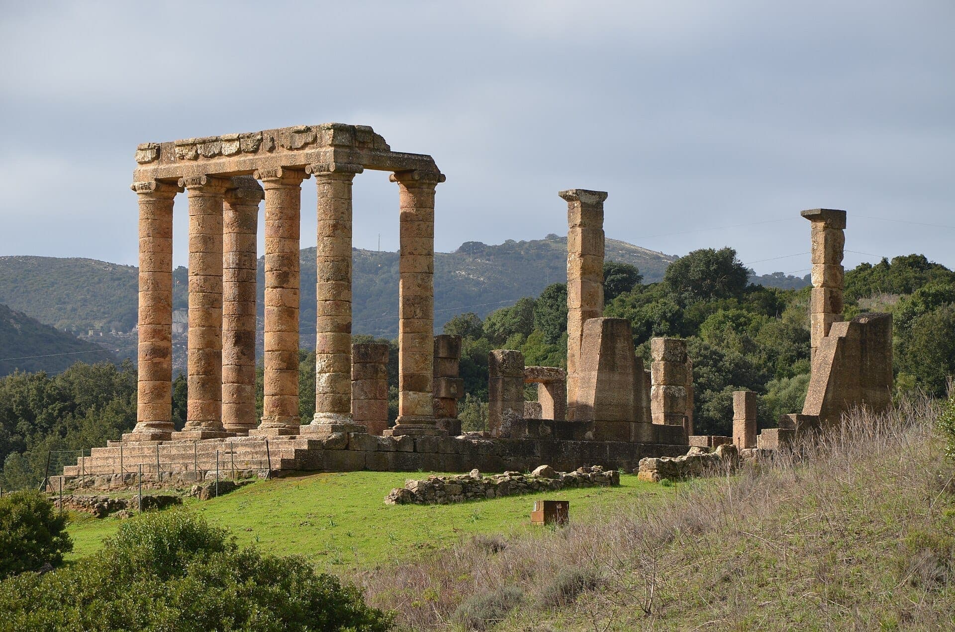 Las antiguas columnas y ruinas de piedra del Tempio di Antas se elevan sobre la hierba verde y los árboles en las boscosas colinas del Sulcis-Iglesiente de Cerdeña.