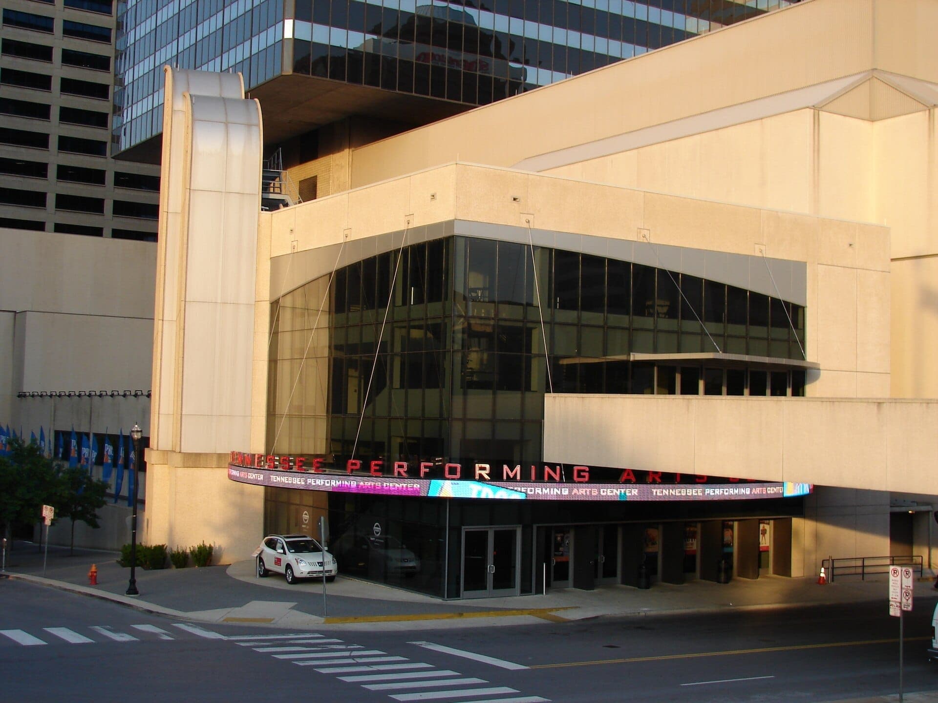 The modern facade of the Tennessee Performing Arts Center in downtown Nashville, featuring large glass windows and a sleek marquee over the entrance.