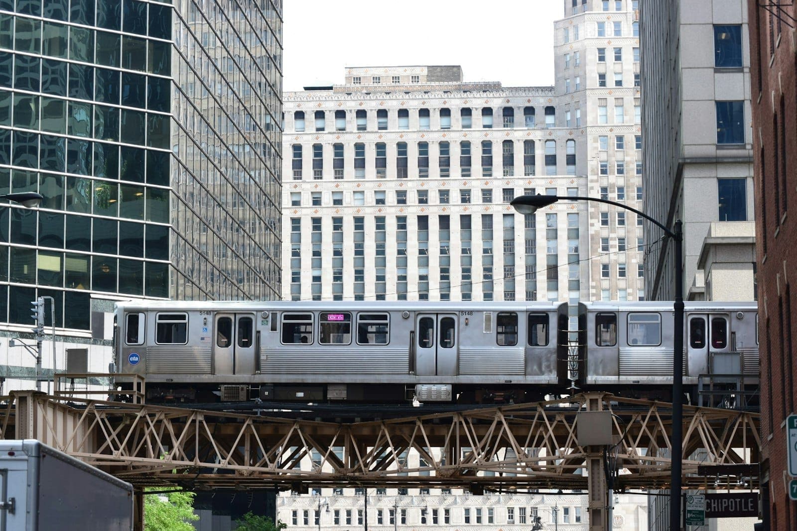 A Chicago elevated CTA train passes between tall buildings in the downtown Loop area, highlighting the city’s historic core and urban energy.