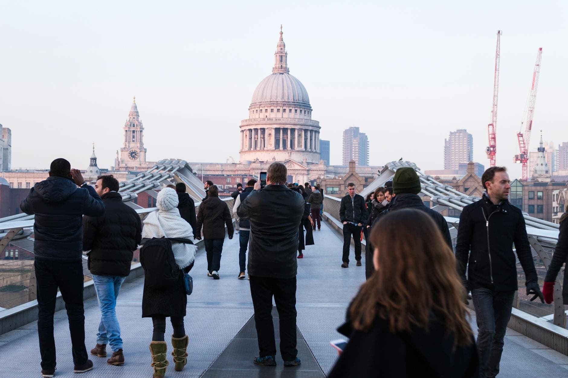 Personas caminando por el Millennium Bridge con la Catedral de St Paul's y el centro de Londres visibles al fondo.