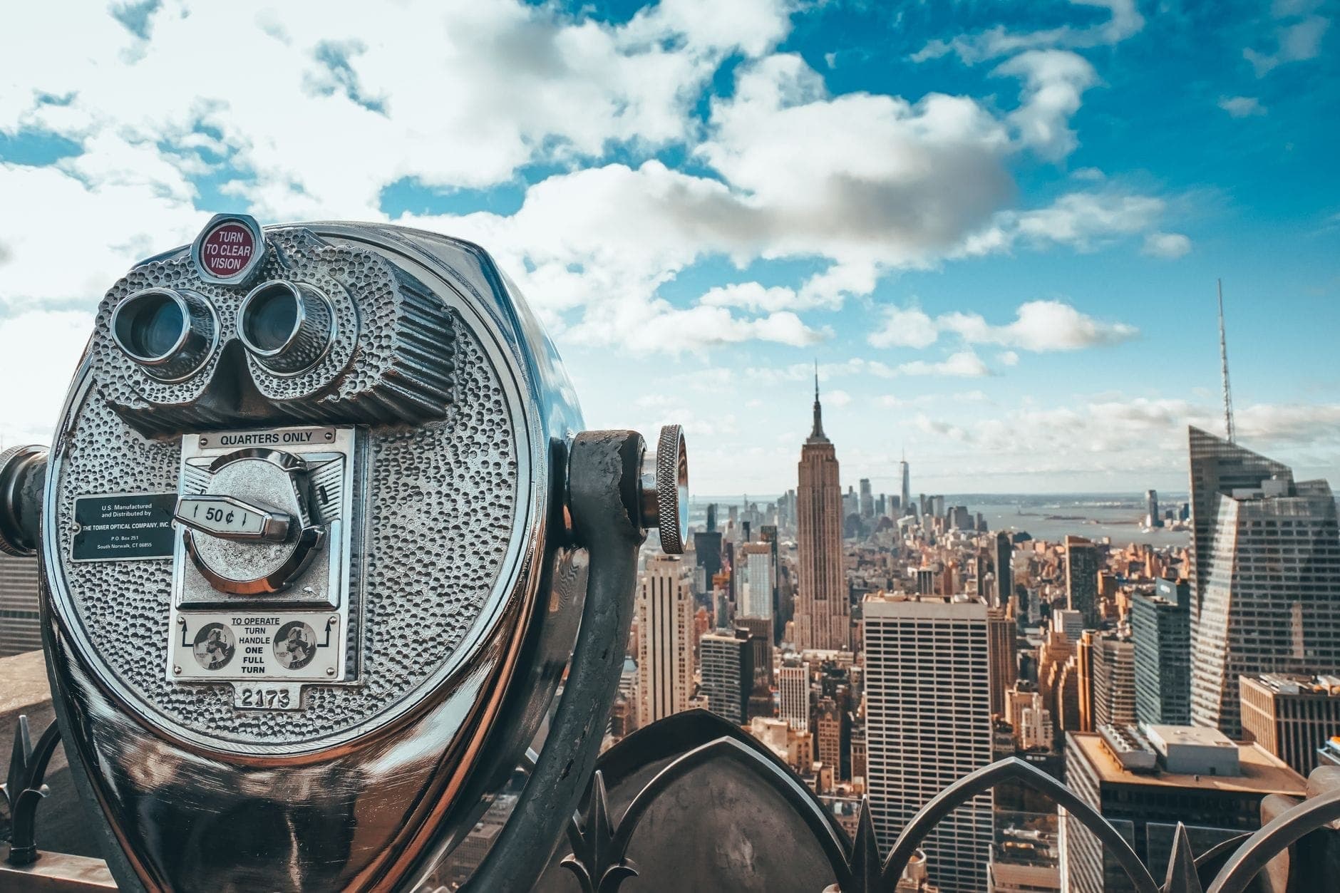 กล้องส่องทางไกลแบบหยอดเหรียญคลาสสิกที่มองเห็นเส้นขอบฟ้าของ New York City พร้อม Empire State Building และตึกระฟ้าที่มองเห็นได้ชัดเจนในวันที่อากาศแจ่มใส