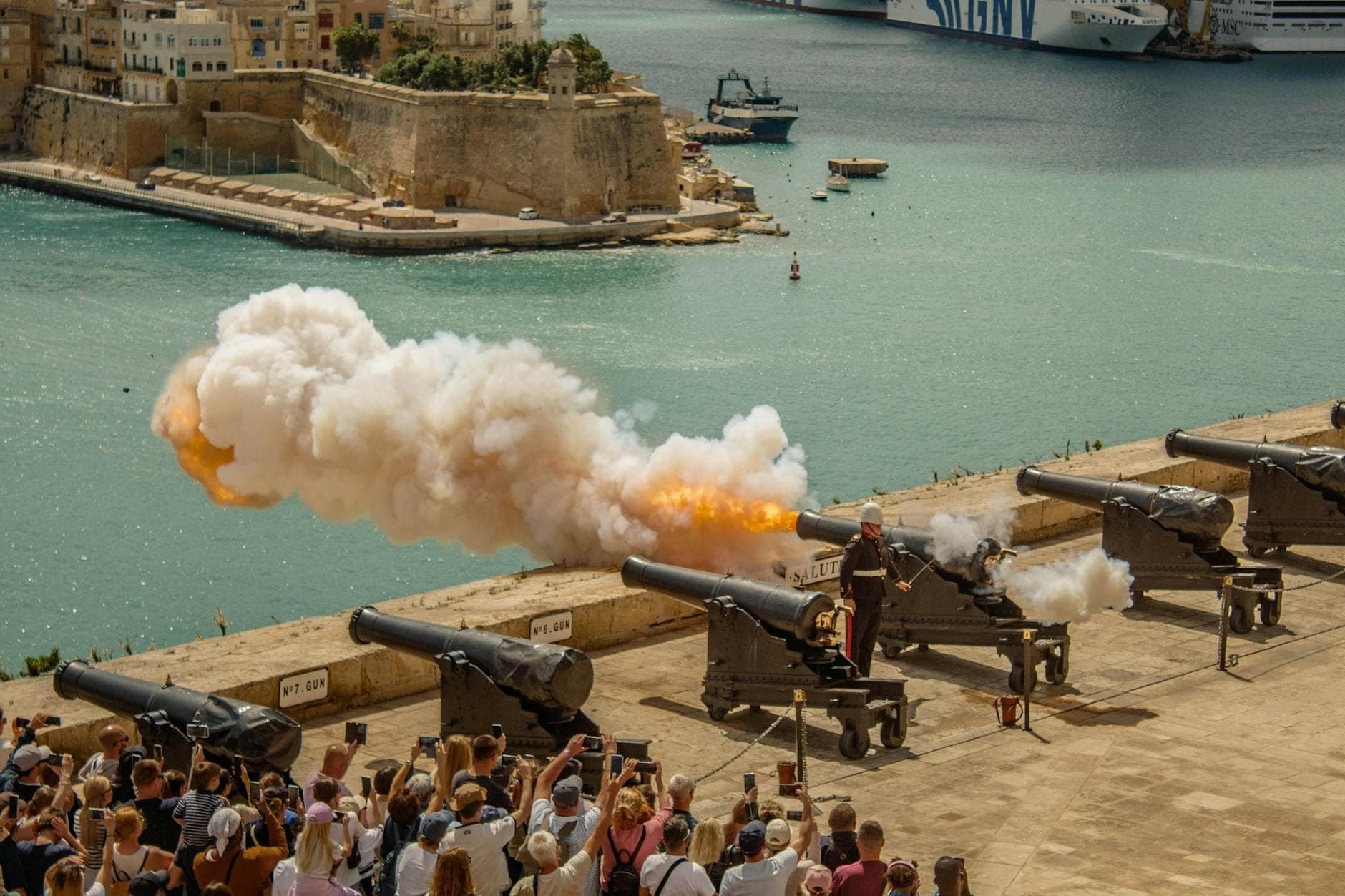 Crowd watching cannon firing at Upper Barrakka Gardens overlooking the Grand Harbour in Valletta, Malta.