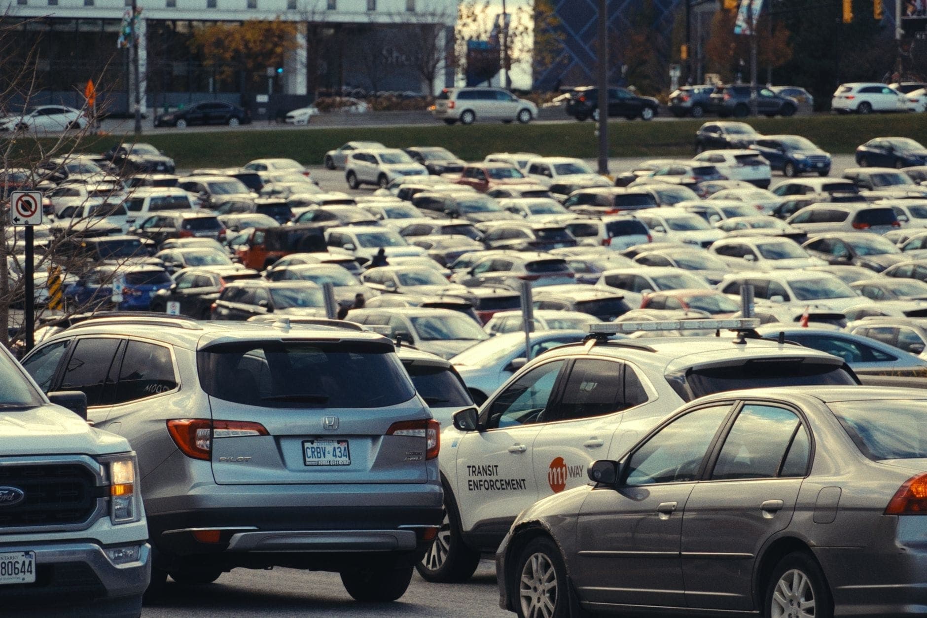 Parcheggio dell'aeroporto affollato e pieno di auto davanti ai terminal. Alcuni veicoli hanno targhe dell'Ontario, suggerendo una località canadese.