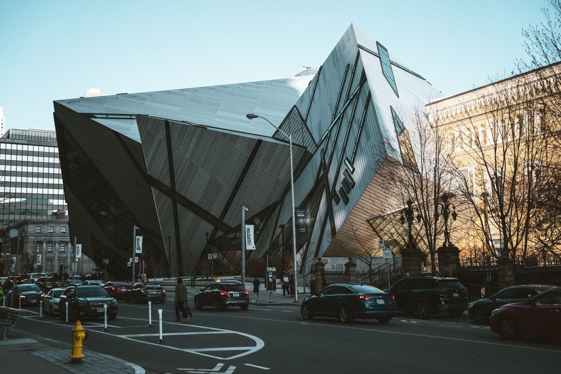 Vista de la calle de la llamativa entrada Crystal moderna del Royal Ontario Museum en Toronto con autos y peatones afuera.