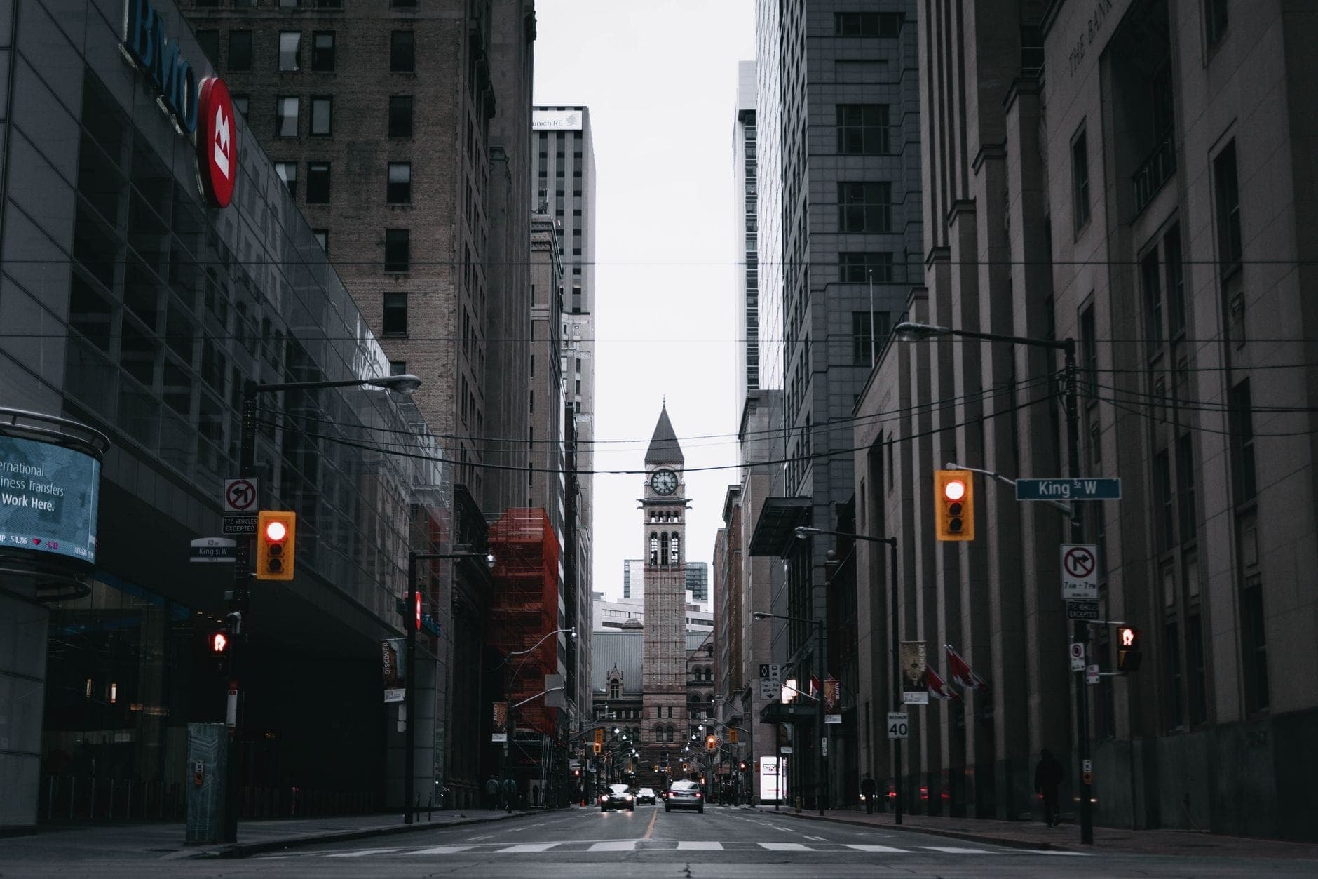 Street view of King Street West in Toronto with historic clock tower in the distance, surrounded by urban buildings and festival zone signage.