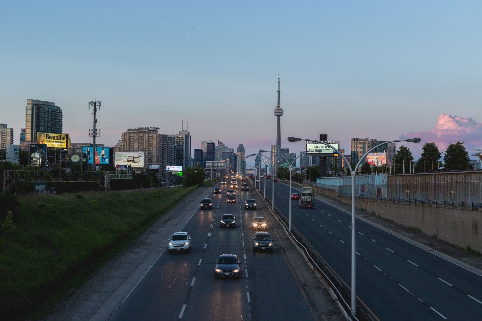 Vista del horizonte de Toronto con la CN Tower y tráfico saliendo de la ciudad por la autopista al anochecer.