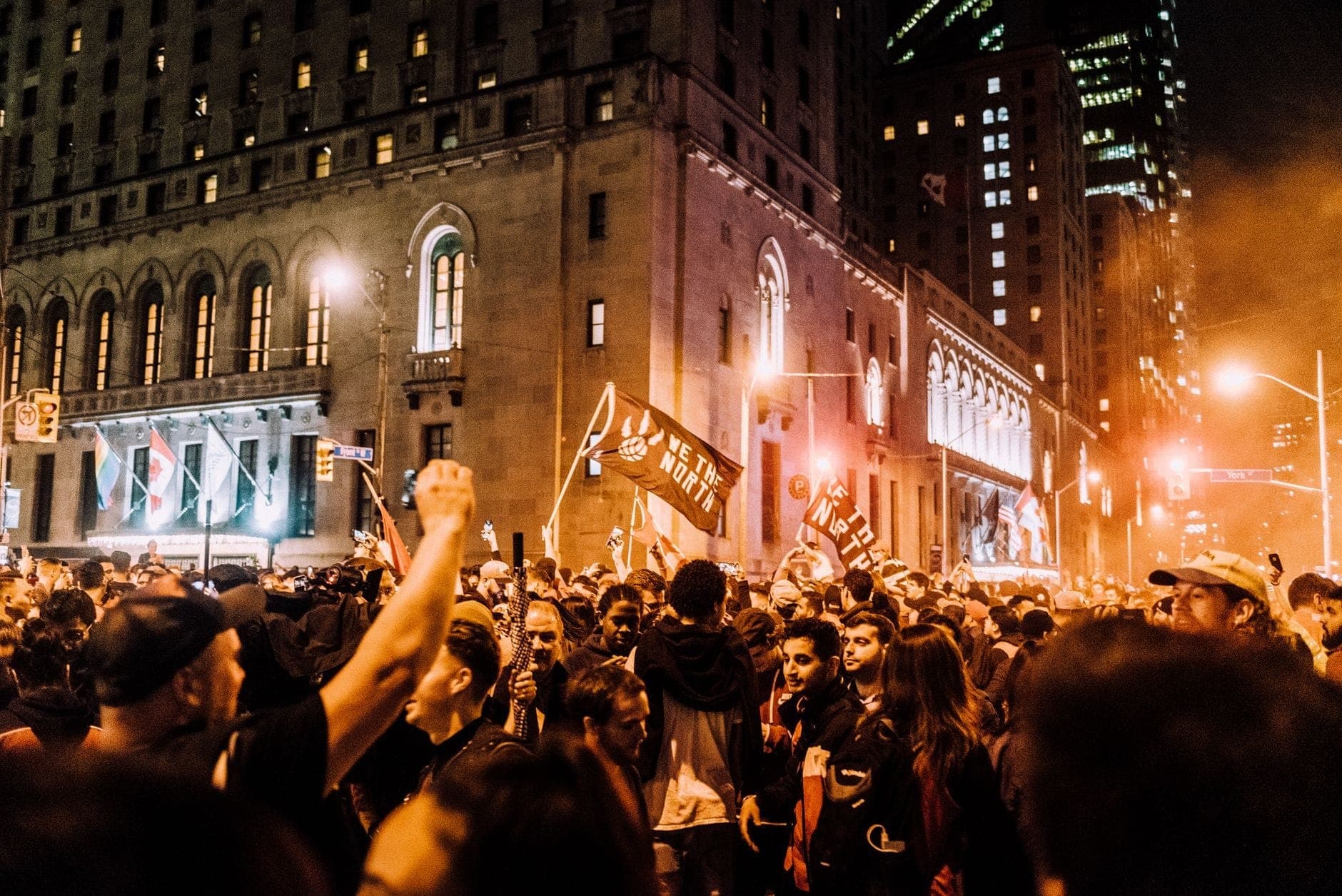 Grande folla densa di persone che riempie una strada di Toronto di notte con edifici e luci della città sullo sfondo.