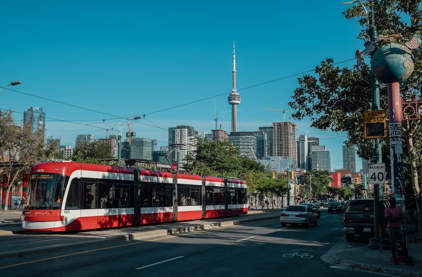 Tram di Toronto che percorre il centro città con la CN Tower e lo skyline urbano sullo sfondo in una giornata di sole.