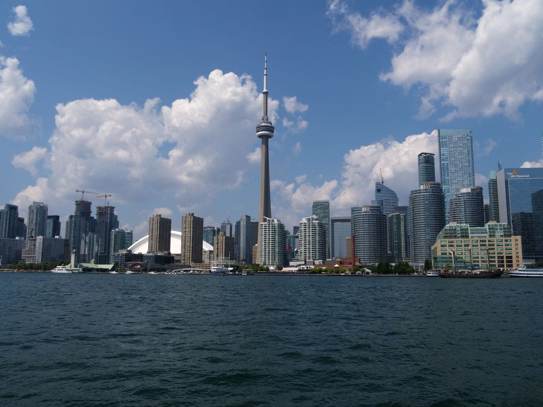 Vista diurna del paseo marítimo de Toronto con la CN Tower, el Rogers Centre y hoteles modernos, ideal para estancias familiares cerca de las principales atracciones.