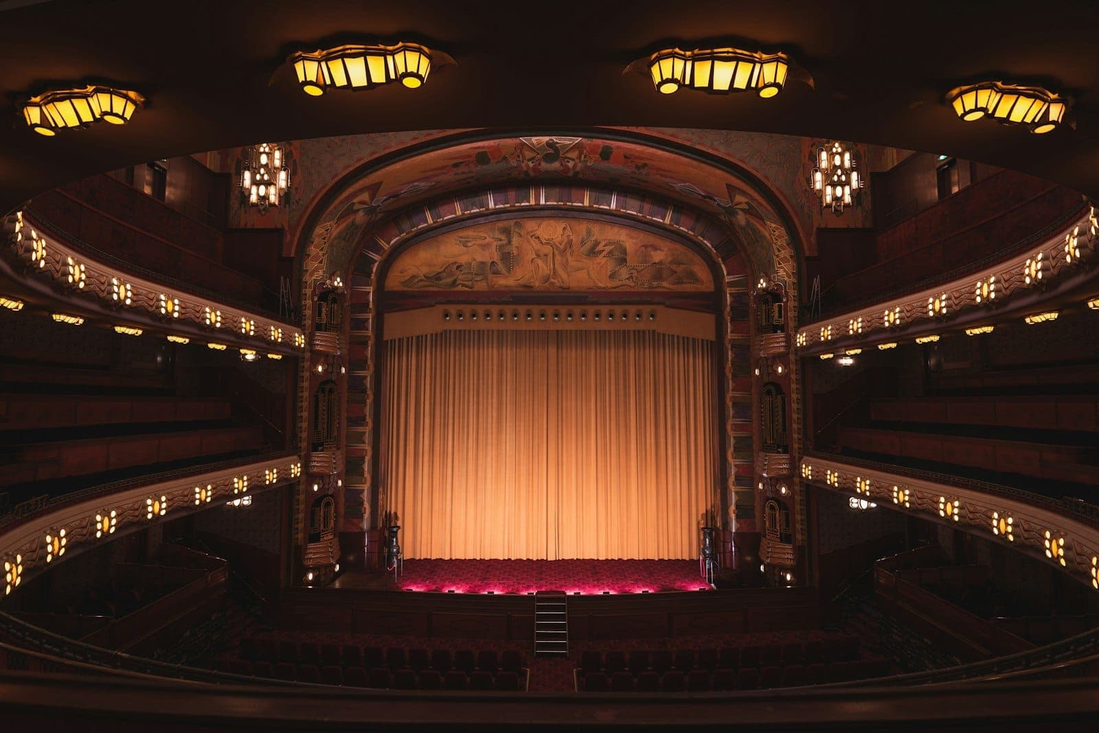 Eleganter Innenblick auf das Pathé Tuschinski Theater in Amsterdam, mit Art-déco-Leuchten, verzierten Balkonen und einem goldenen Bühnenvorhang.