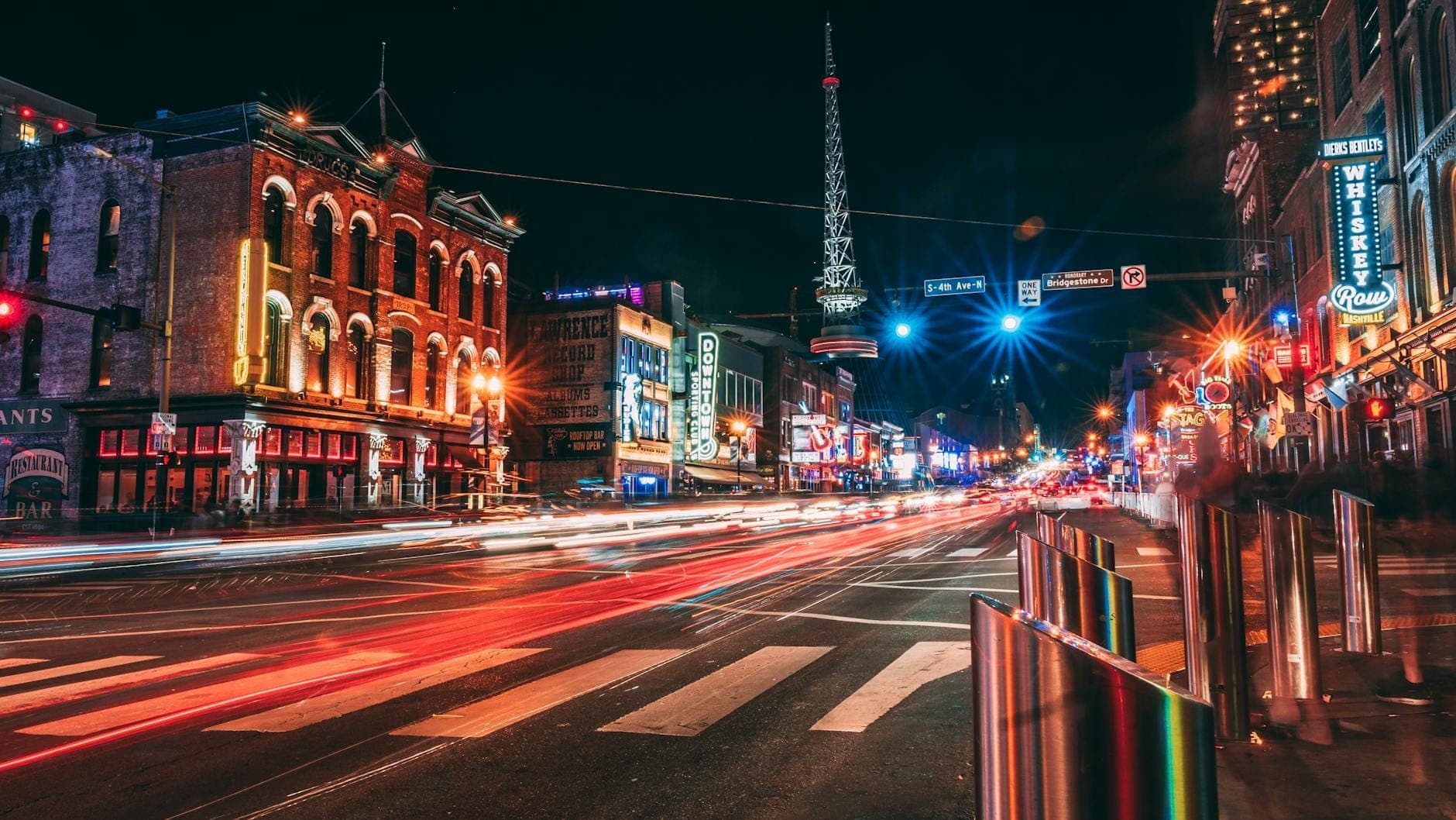 Nashvilles neonbeleuchteter Broadway bei Nacht, mit historischen Musikclubs aus Backstein, lebhaften Lichtern und geschäftigem Straßenleben im Herzen der Stadt.