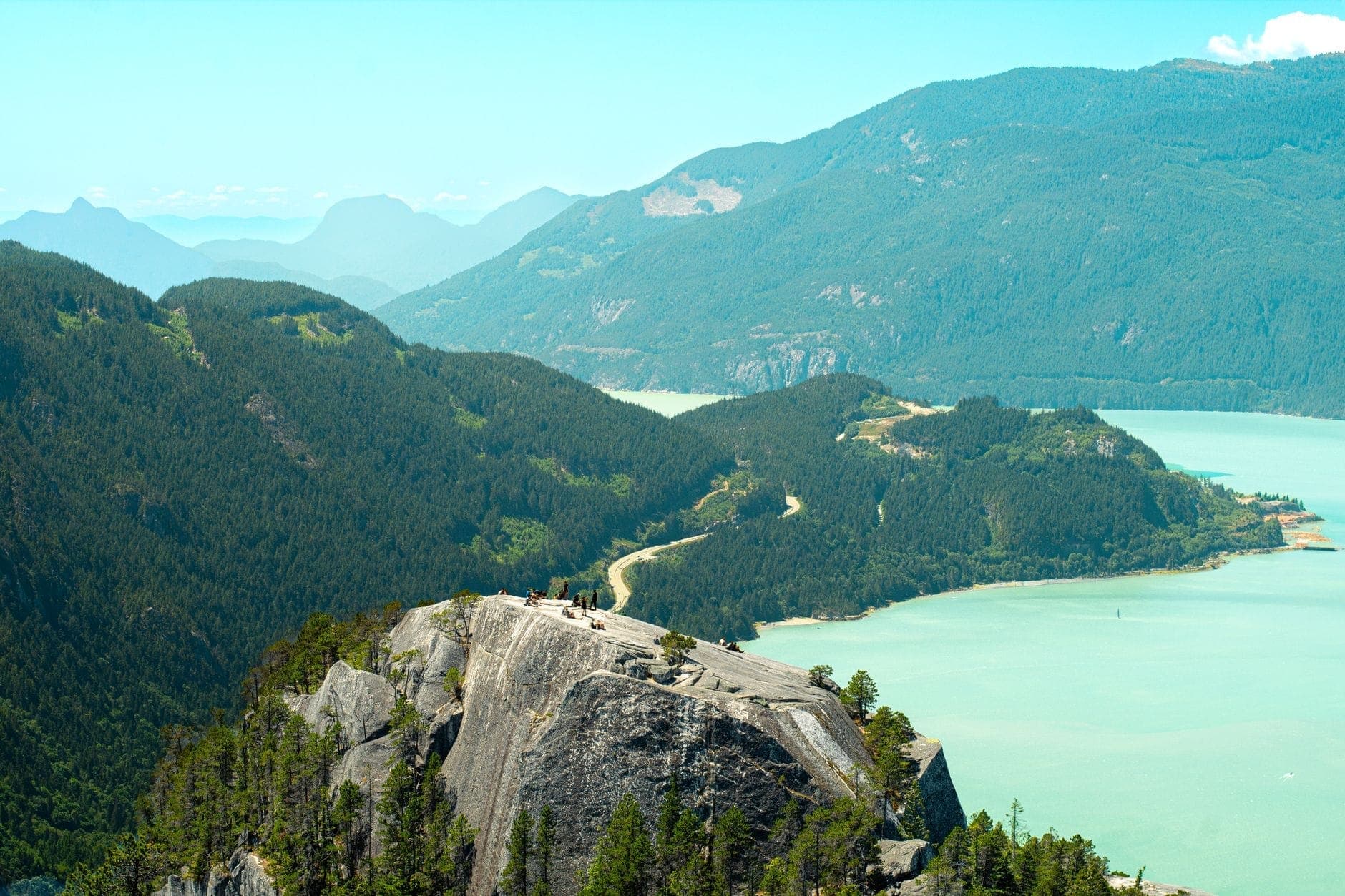 วิวกว้างเหนือ Howe Sound พร้อมทางหลวงคดเคี้ยว ภูเขาสีเขียว และโขดหินโผล่ — ทิวทัศน์คลาสสิกของ Sea to Sky Corridor ในวันที่แสงแดดสดใส