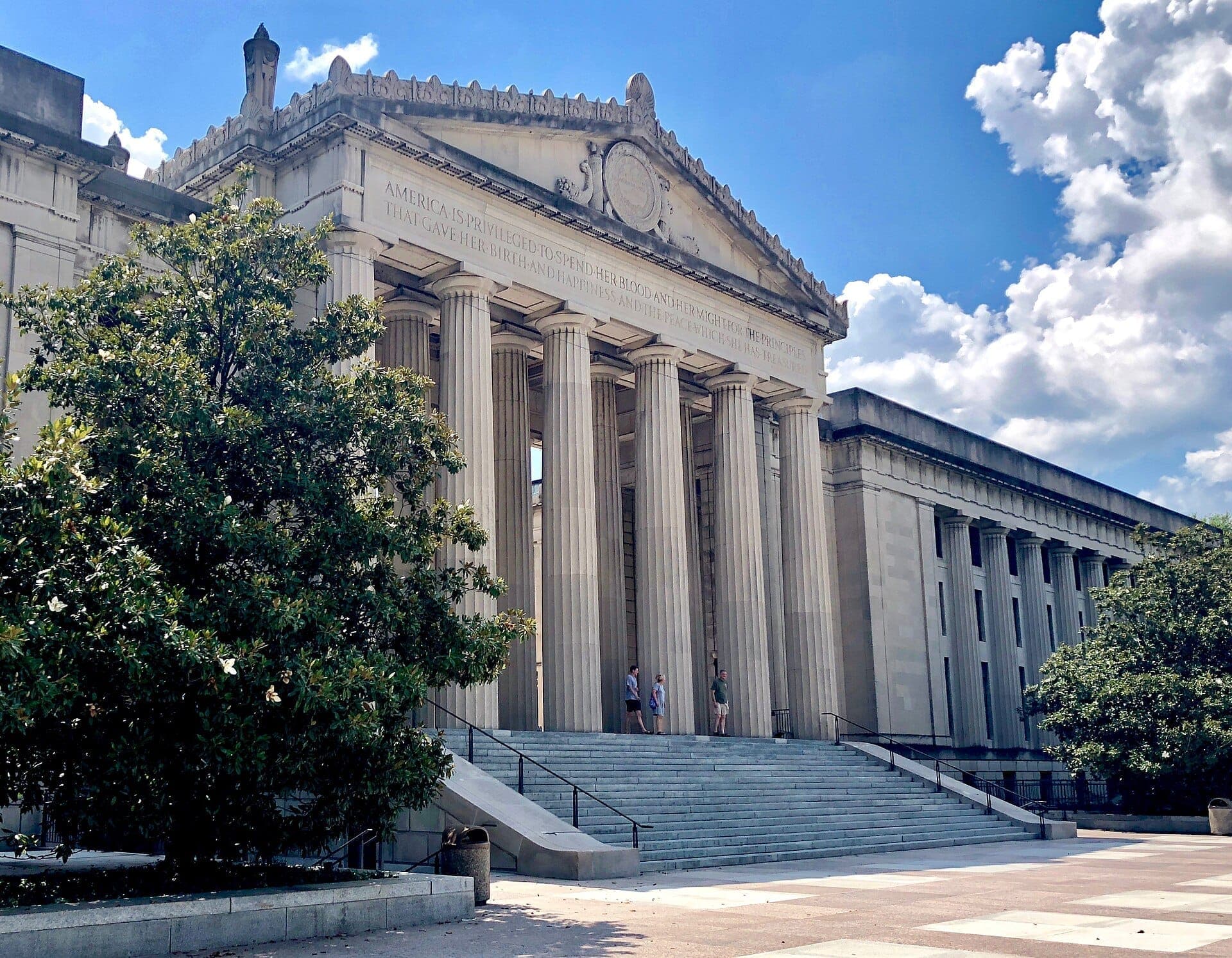 Die prächtige Beaux-Arts-Fassade des War Memorial Auditorium mit hohen Säulen und Stufen, eingerahmt von grünen Bäumen unter einem strahlend blauen Himmel über Nashville.