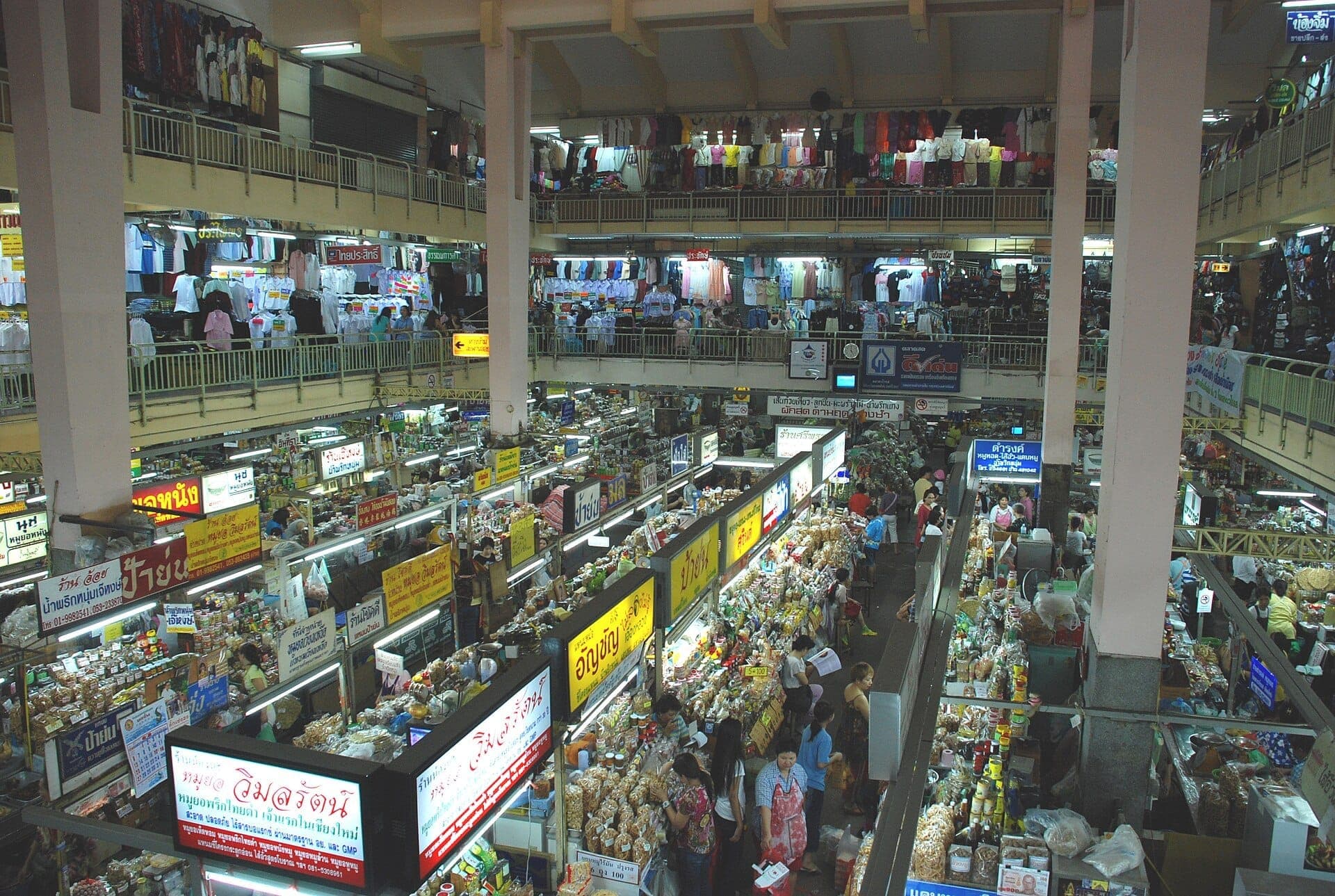 Innenansicht des Warorot-Markts mit belebten Ständen, die Lebensmittel und Kleidung verkaufen, einer Menschenmenge von Einkäufern und bunten thailändischen Schildern auf mehreren Etagen.