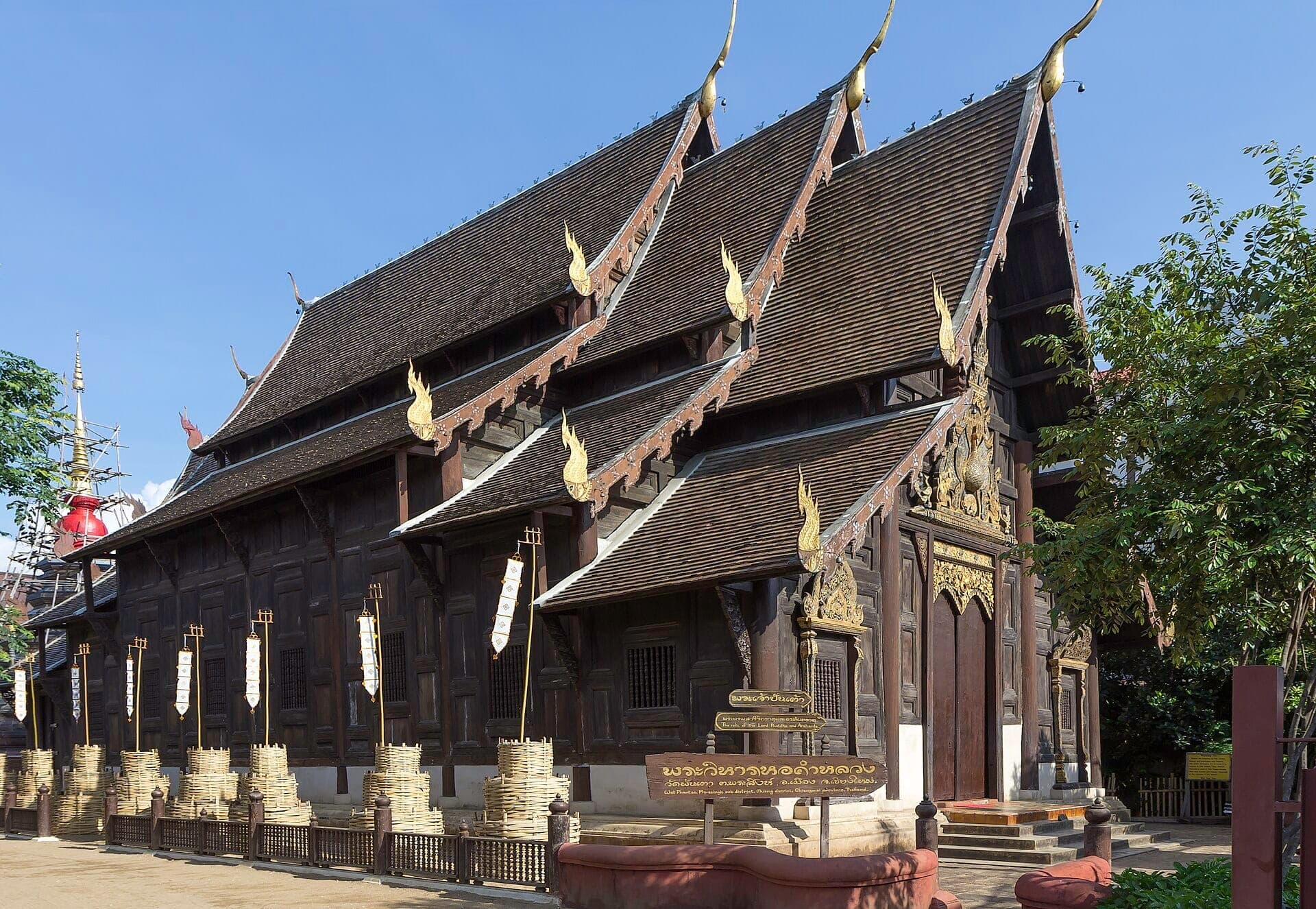 Frontansicht des Wat Phan Tao Tempels in Chiang Mai mit seinem kunstvoll verzierten Teakholz-Exterieur, goldenen Schnitzereien und traditionellen Lanna-Architekturdetails unter klarem Himmel.