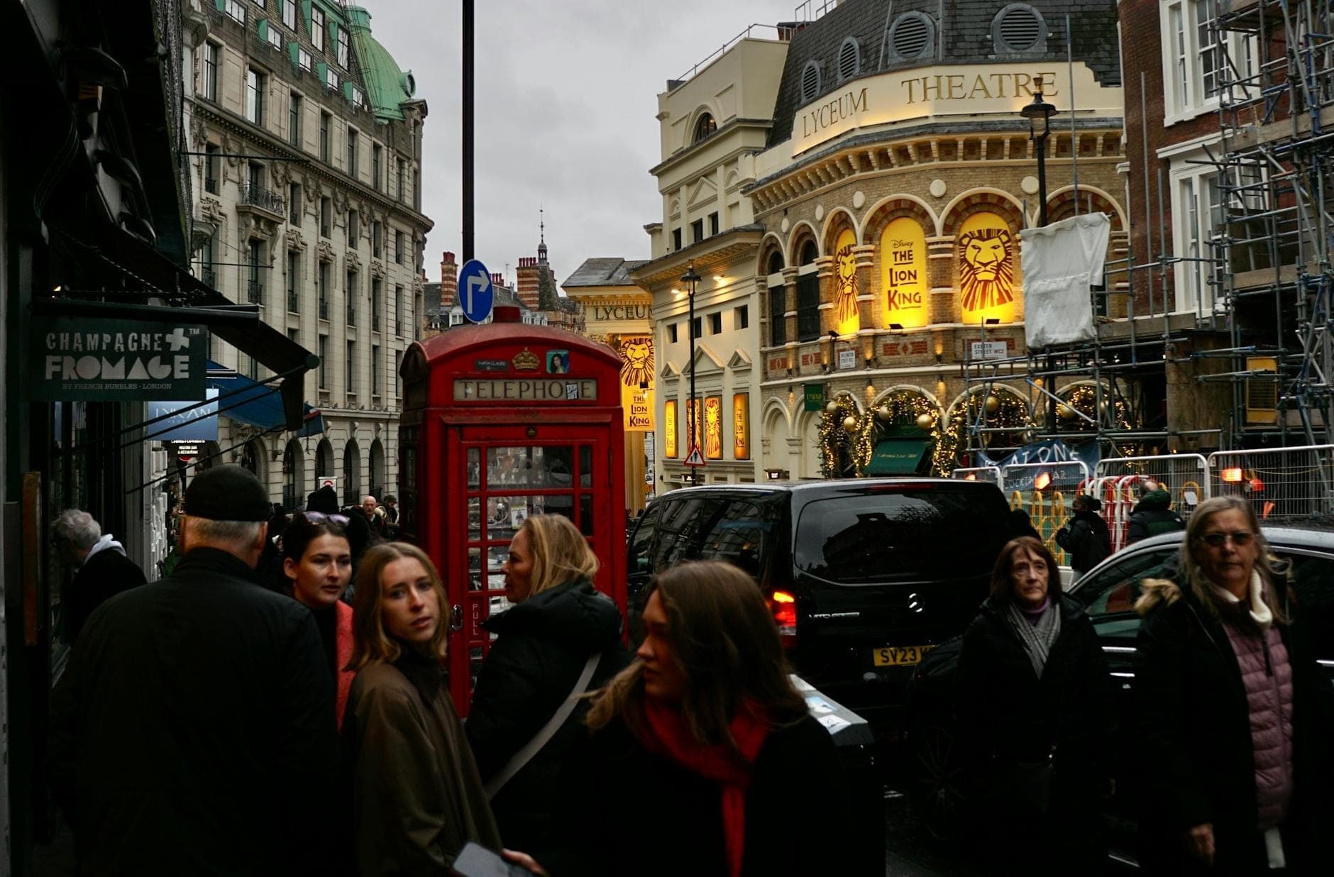 Zatłoczona ulica w londyńskim West End z Lyceum Theatre, czerwoną budką telefoniczną i przechodniami, ukazująca klasyczny zabytek teatralny i tętniącą życiem atmosferę.