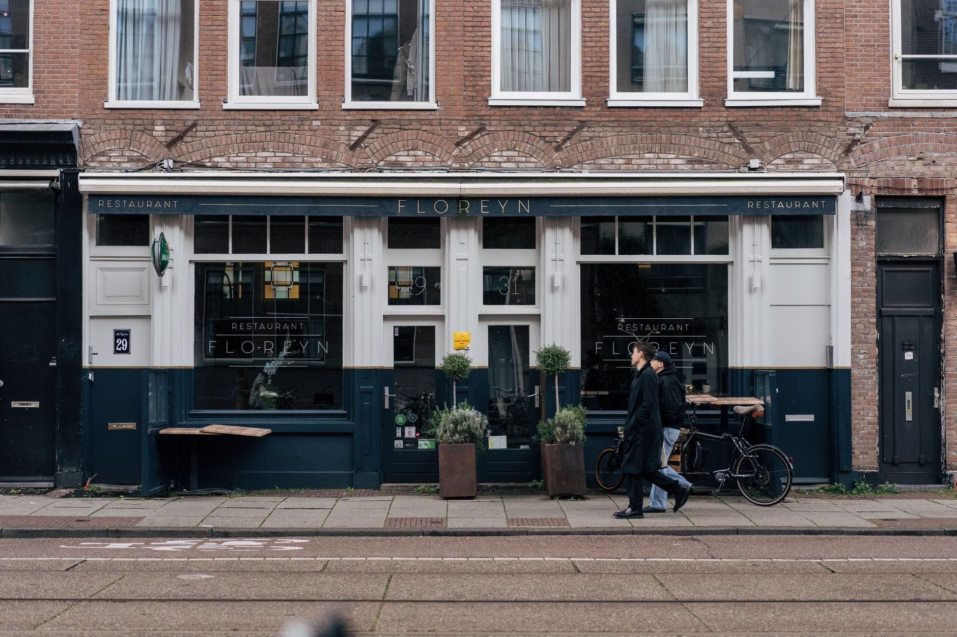Straßenansicht des Restaurant Floreyn in Amsterdam, ein modernes Restaurant mit Menschen, die an seiner Fassade auf einer Stadtstraße vorbeigehen