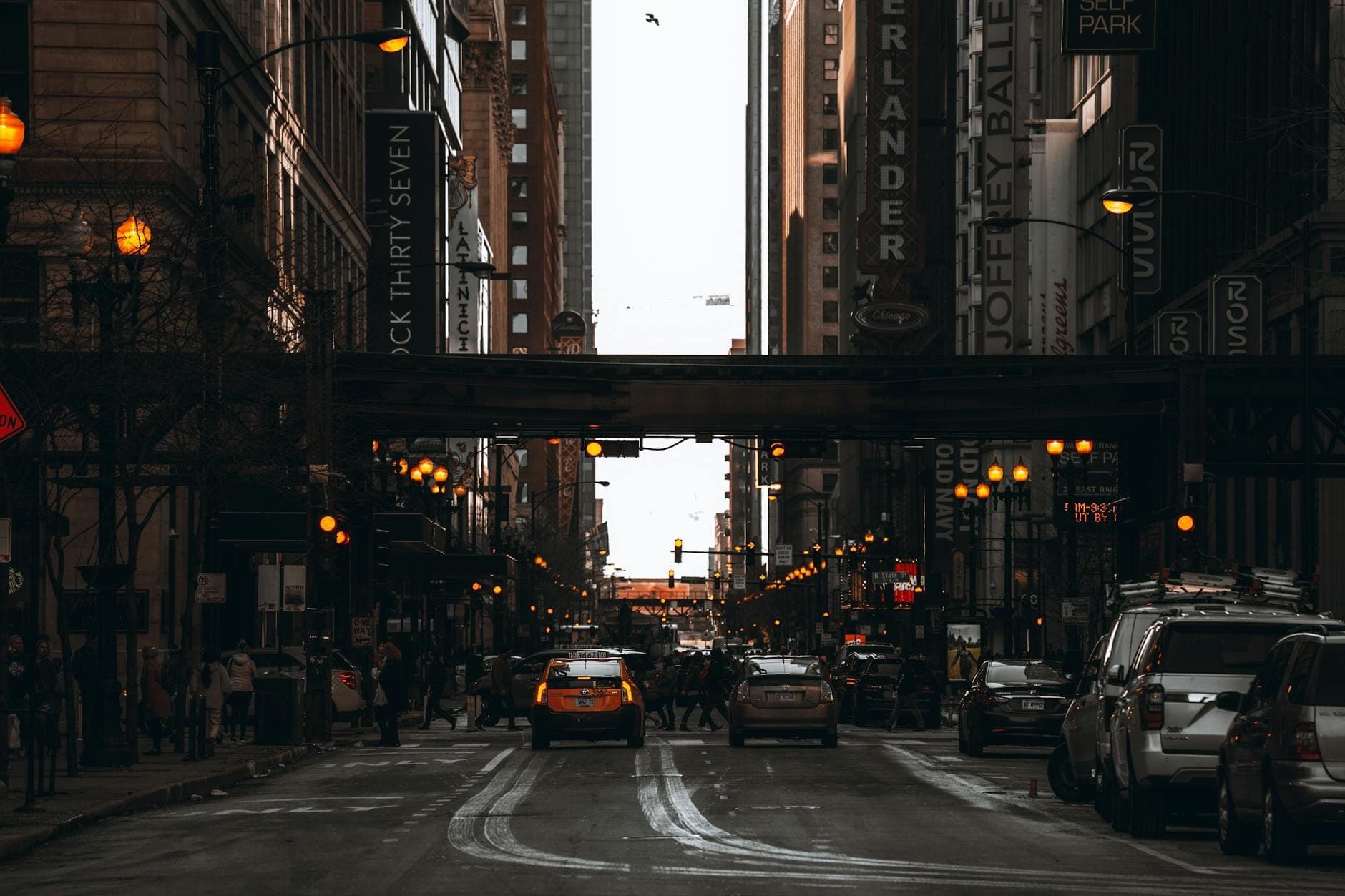 Busy street scene in Chicago’s downtown with cars, people, tall buildings, and restaurant and theater signs along the road.