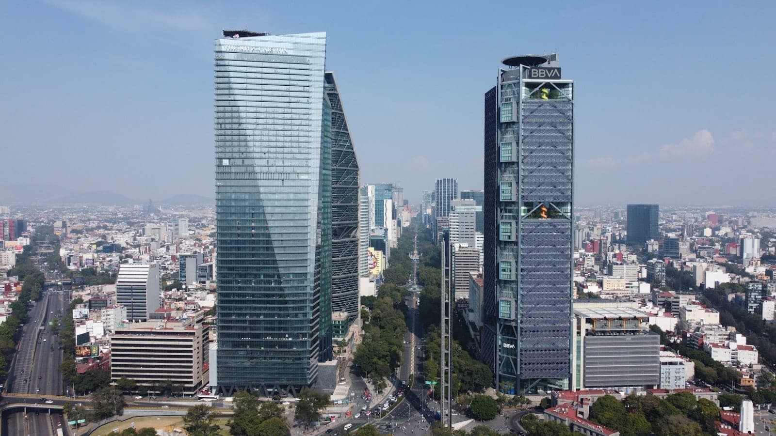 ภาพมุมสูง Paseo de la Reforma ของเม็กซิโกซิตี้ ตึกระฟ้าทันสมัย ถนนใหญ่เรียงต้นไม้ และย่านที่พักขยายตัว ใต้ท้องฟ้าโปร่งใส